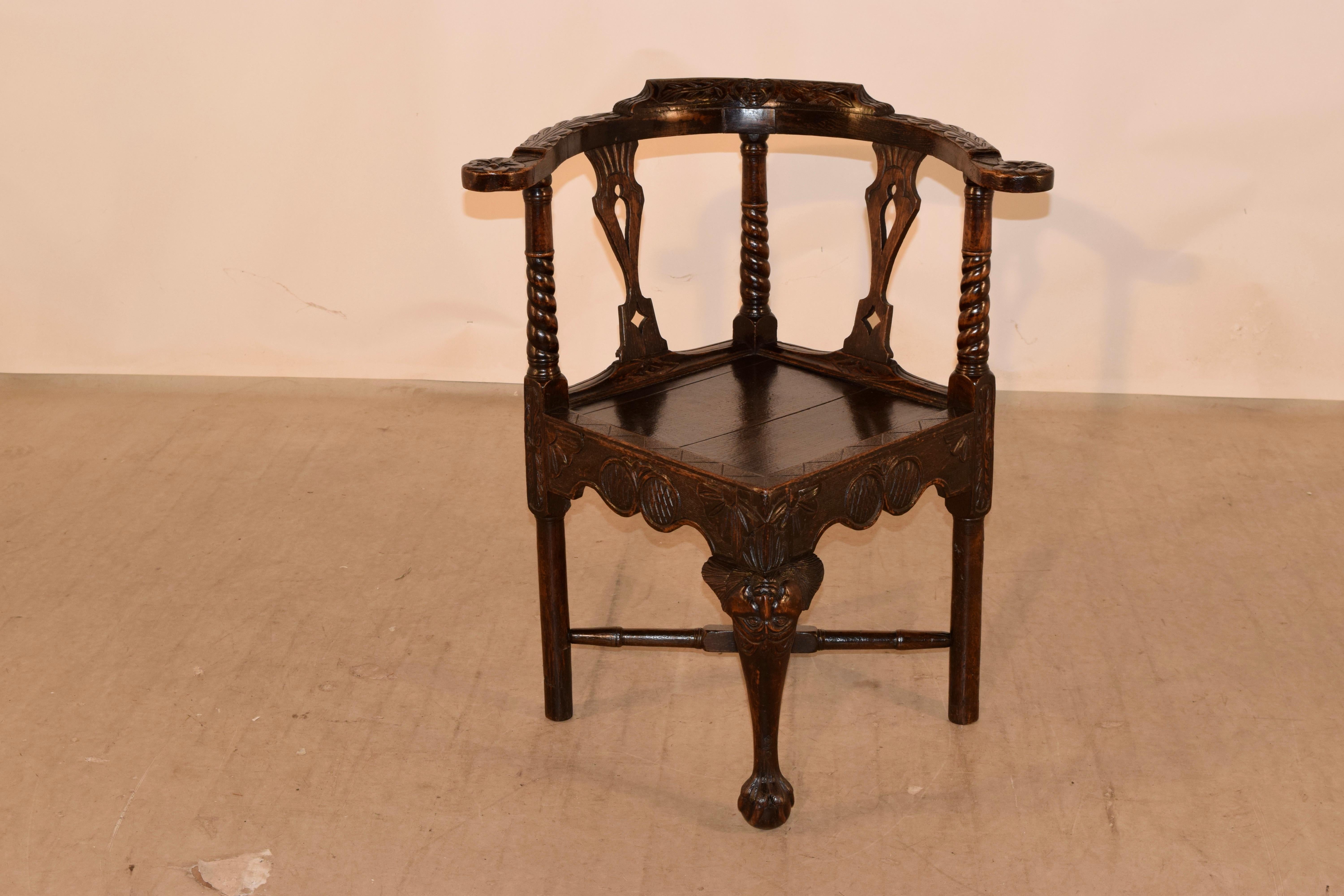 18th century carved oak corner chair from Scotland with a wonderfully carved back, supports and arms, all depicting whimsical faces and leaves. The arm supports are hand turned with twists and are flanked by hand carved open vase back splats. The