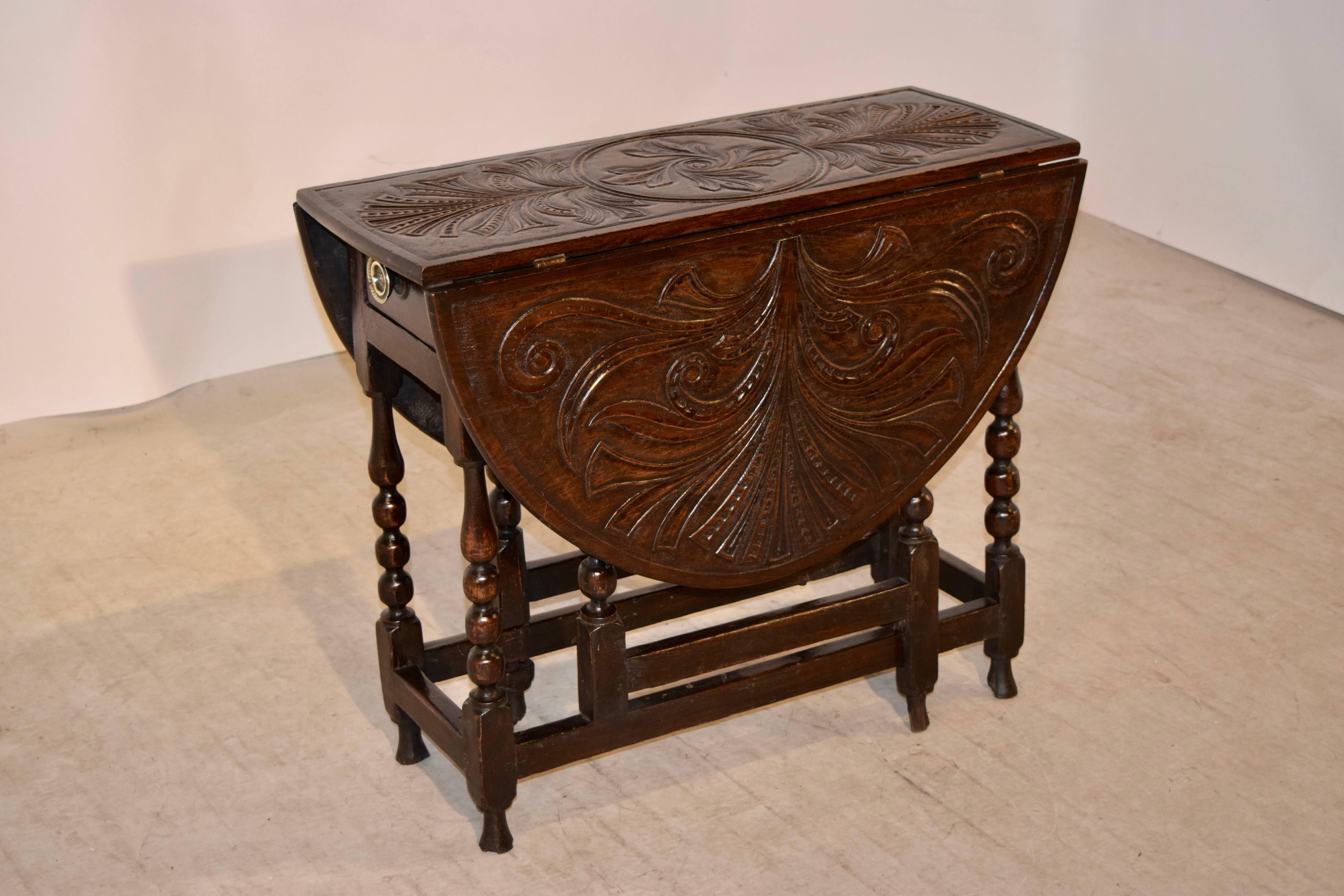 18th century carved oak gateleg from England. The top has a rounded edge and is wonderfully hand-carved all-over the top. The base has a simple apron which contains a single drawer. The legs are hand-turned and have wear from age. They are joined by