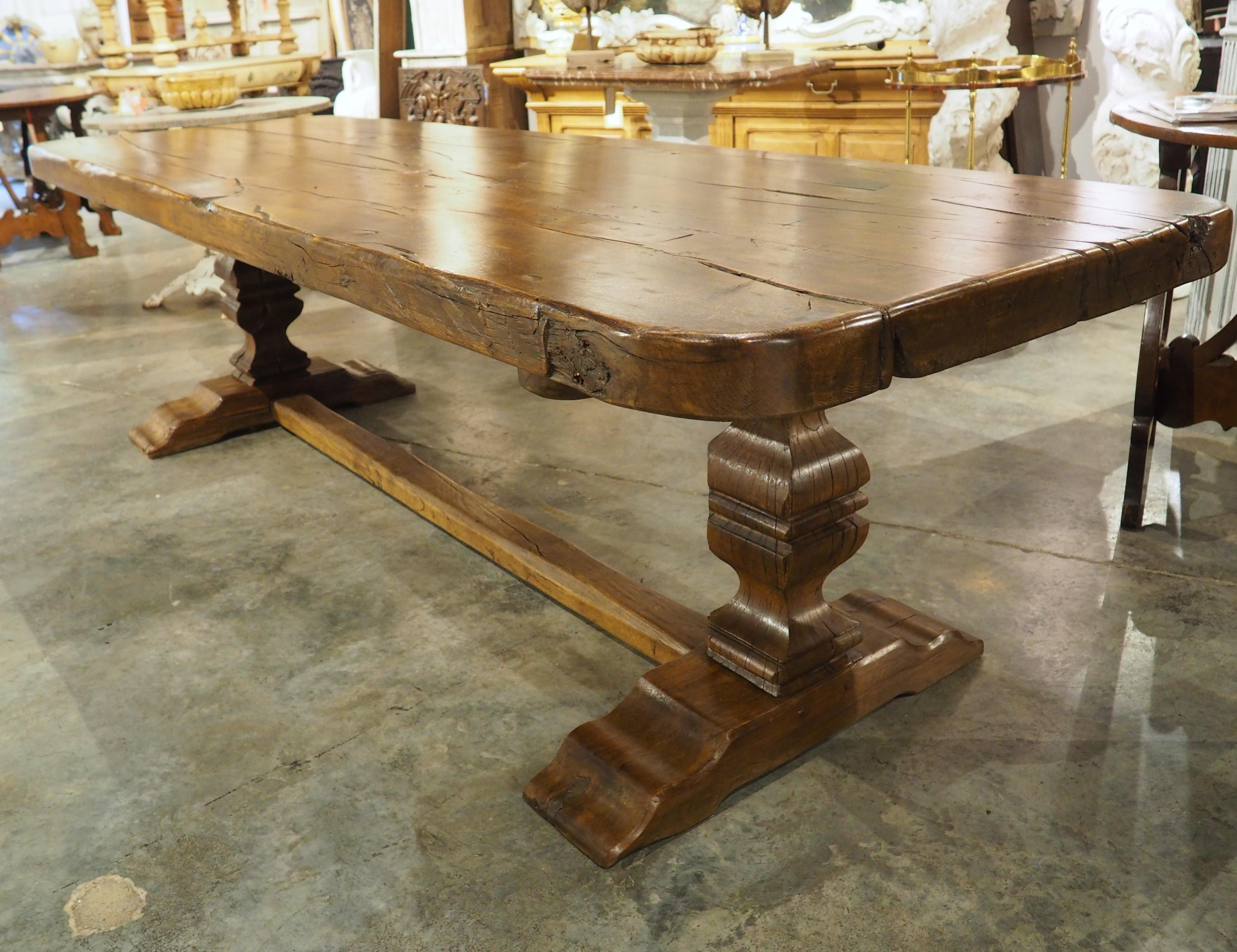 Dating to the 1700s, this monastery dining table was hand-carved in France using oak wood. The three-inch thick top (which is composed of three planks of wood) has undulations to the edges, which enhance the charm of the table. Supported by two