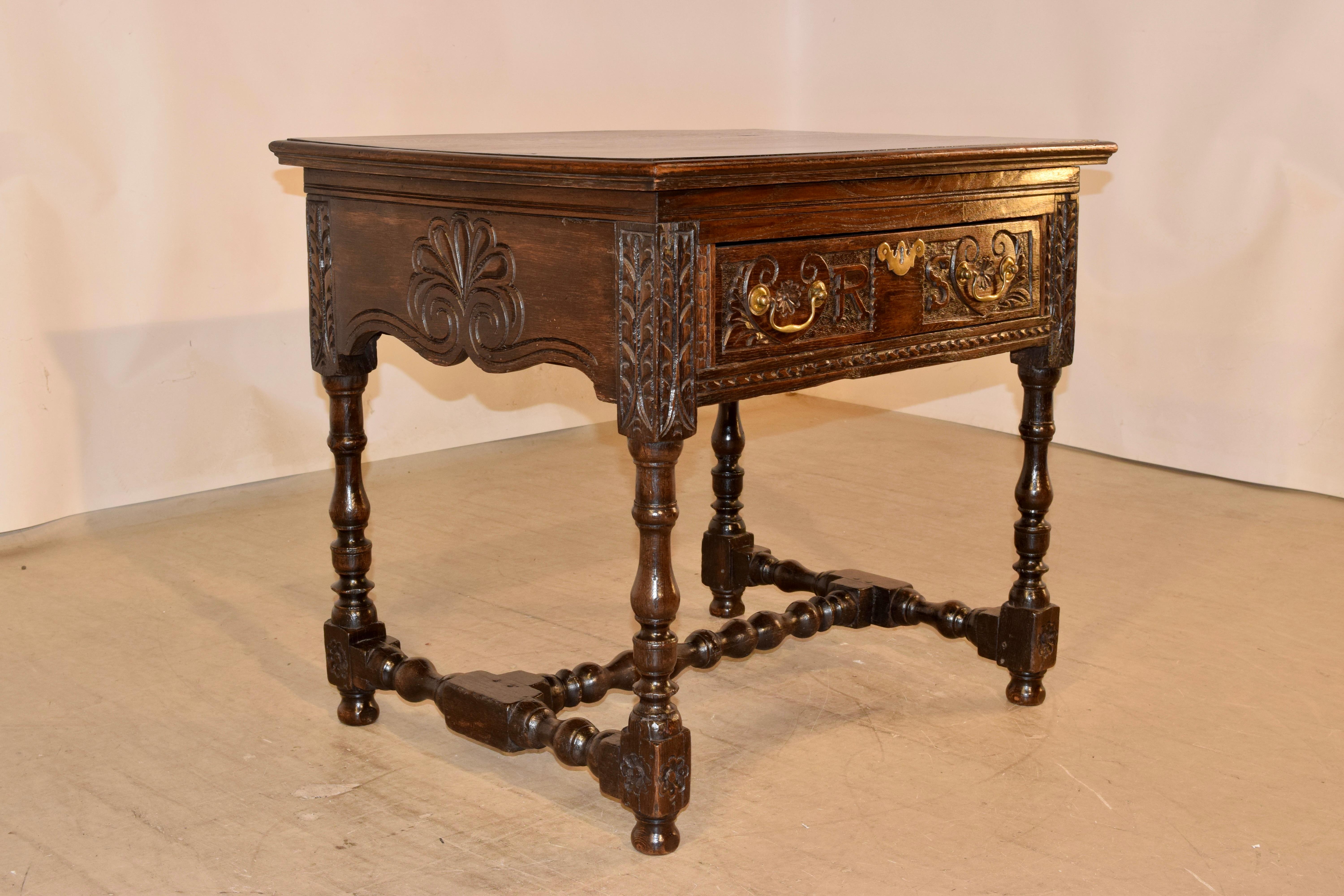 18th century oak side table from England with a three plank top with beveled edges, following down to hand carved decorated and scalloped sides, and containing a single drawer in the front, also with wonderful carved decoration and the initials RS.