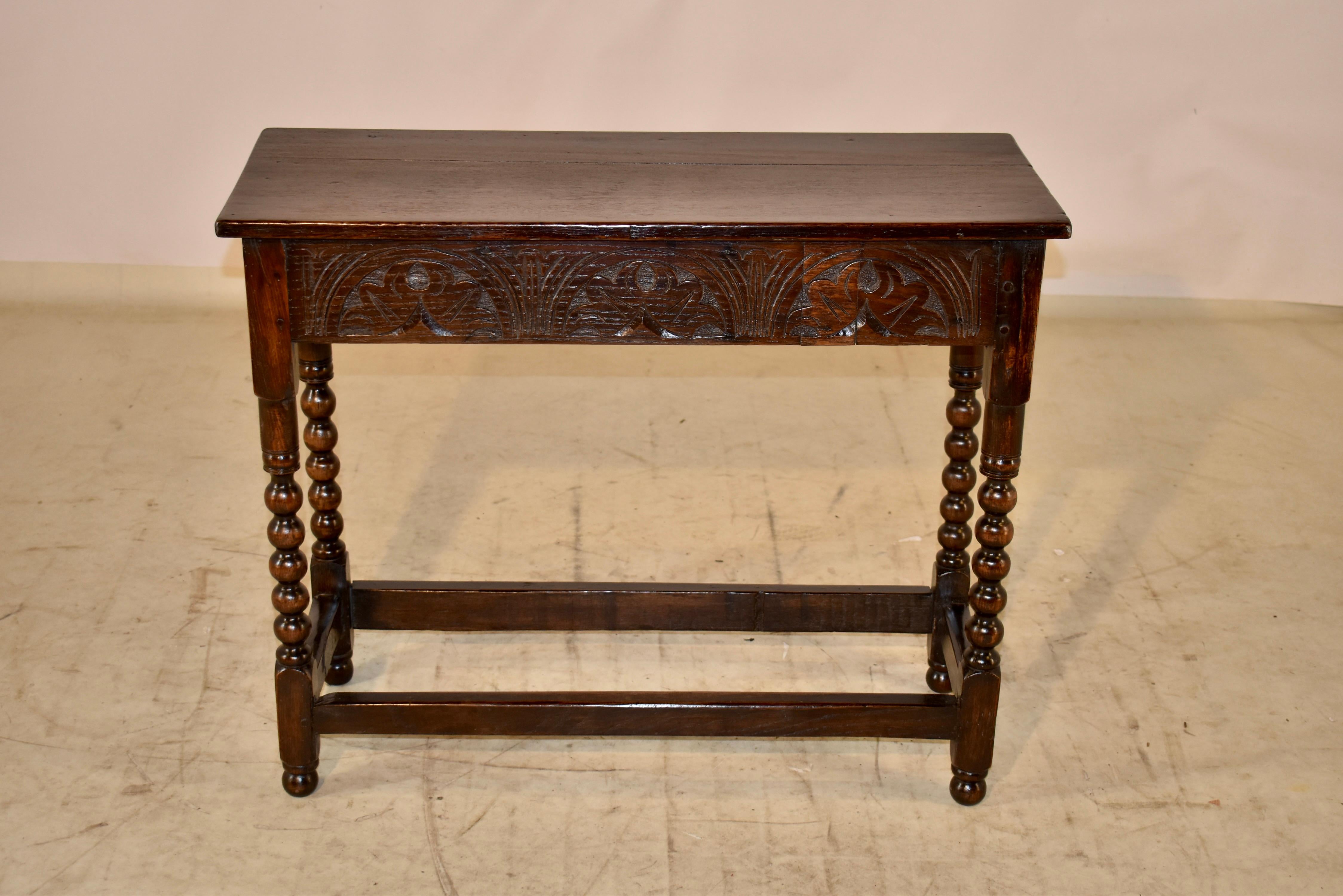 18th century oak side table from England. The top is made from two planks and follows down to a lovely hand carved apron. The apron is carved on all four sides for easy placement in any setting. The table is supported on hand turned bobbin legs,