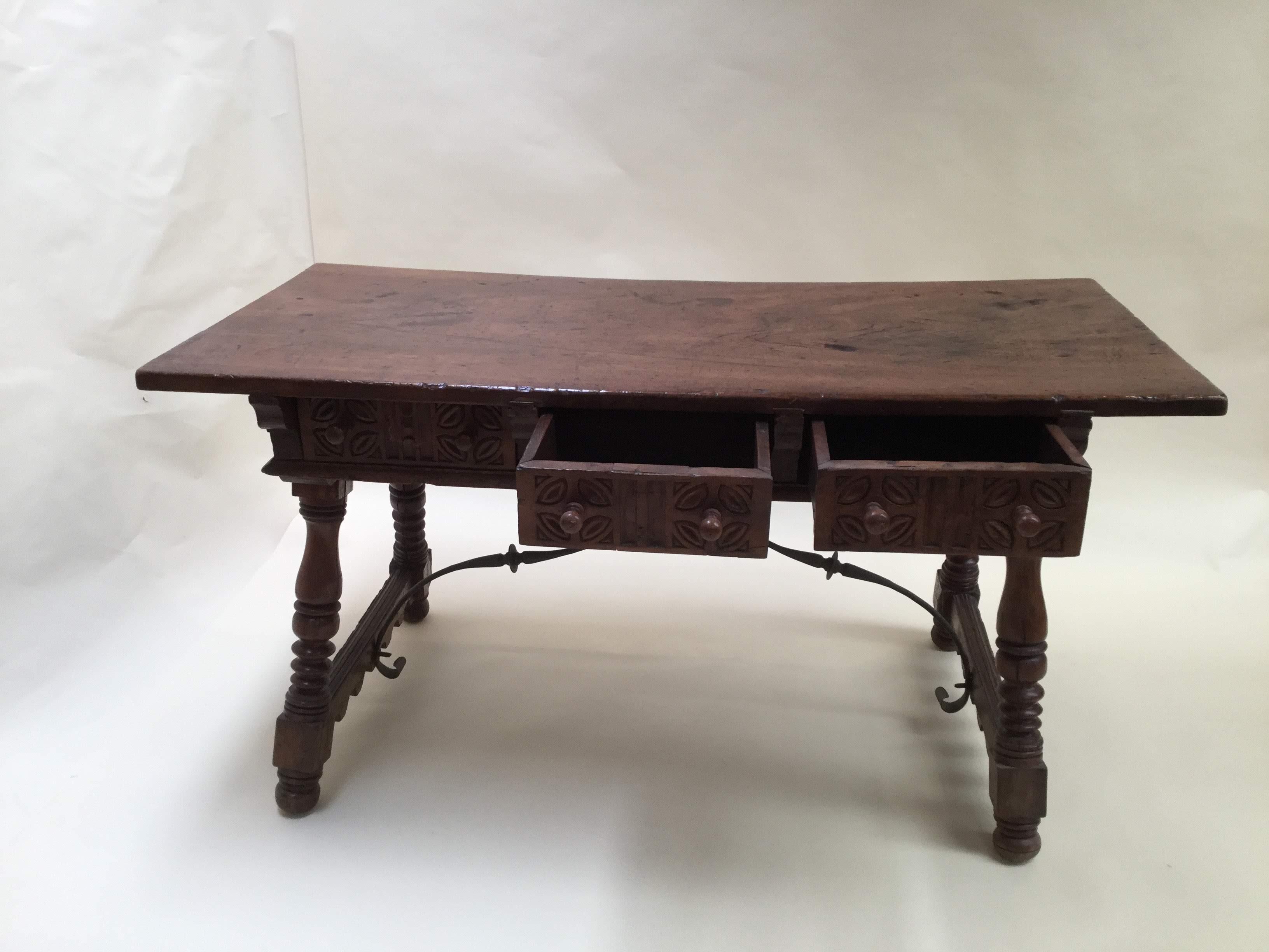 Mid-18th Century.
Spanish bold scale walnut table. This table or desk features five working carved drawers (three at front, two in back) with turning wood work on legs and end supporters joined by a pair of stabile wrought iron stretchers. Waxed