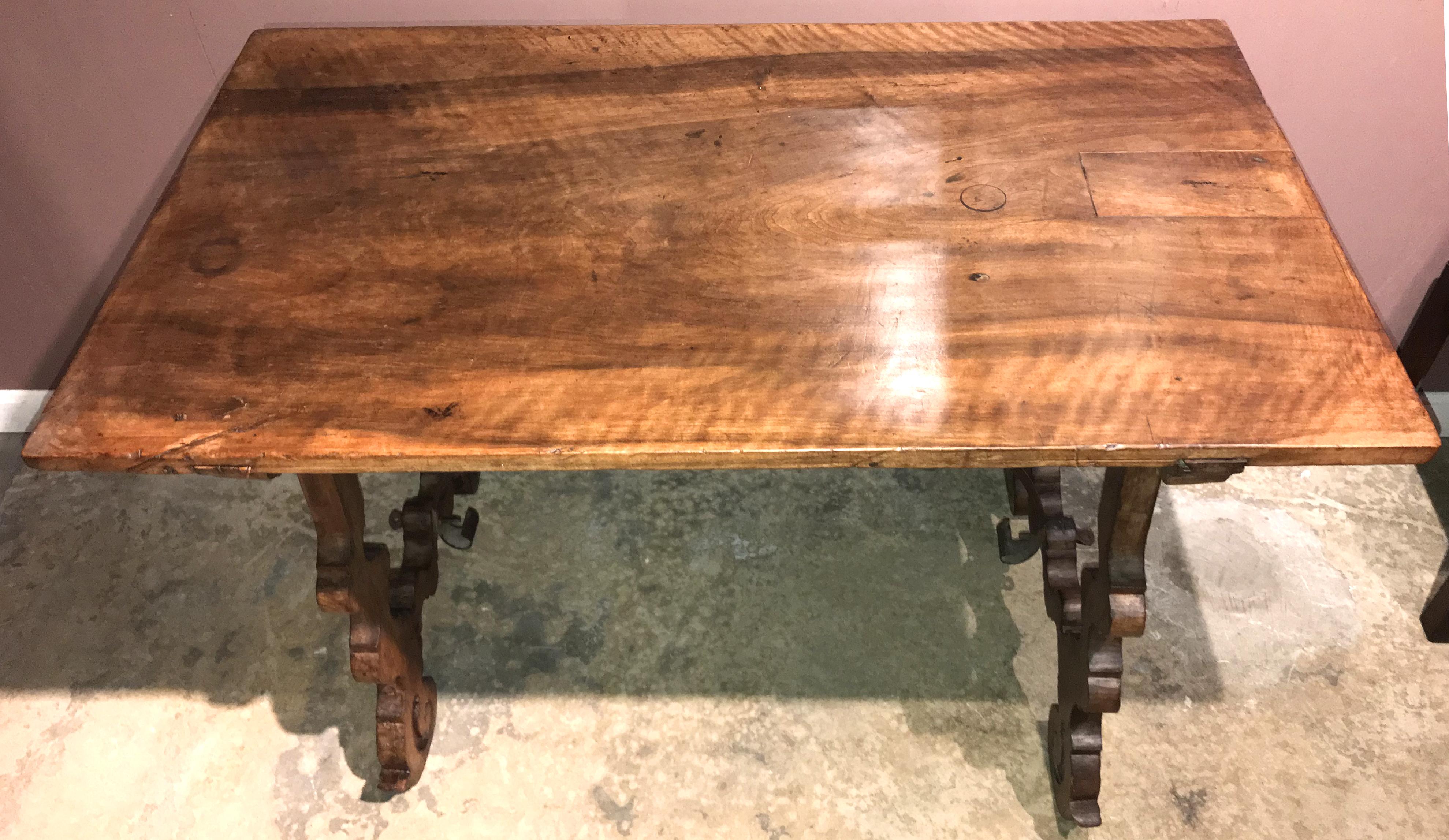 A fine carved walnut trestle table with a rectangular top over two carved shaped legs and supported by overlapping wrought or forged iron stretchers. Spanish in origin, probably dating to the 18th century with great overall patina, old repairs,
