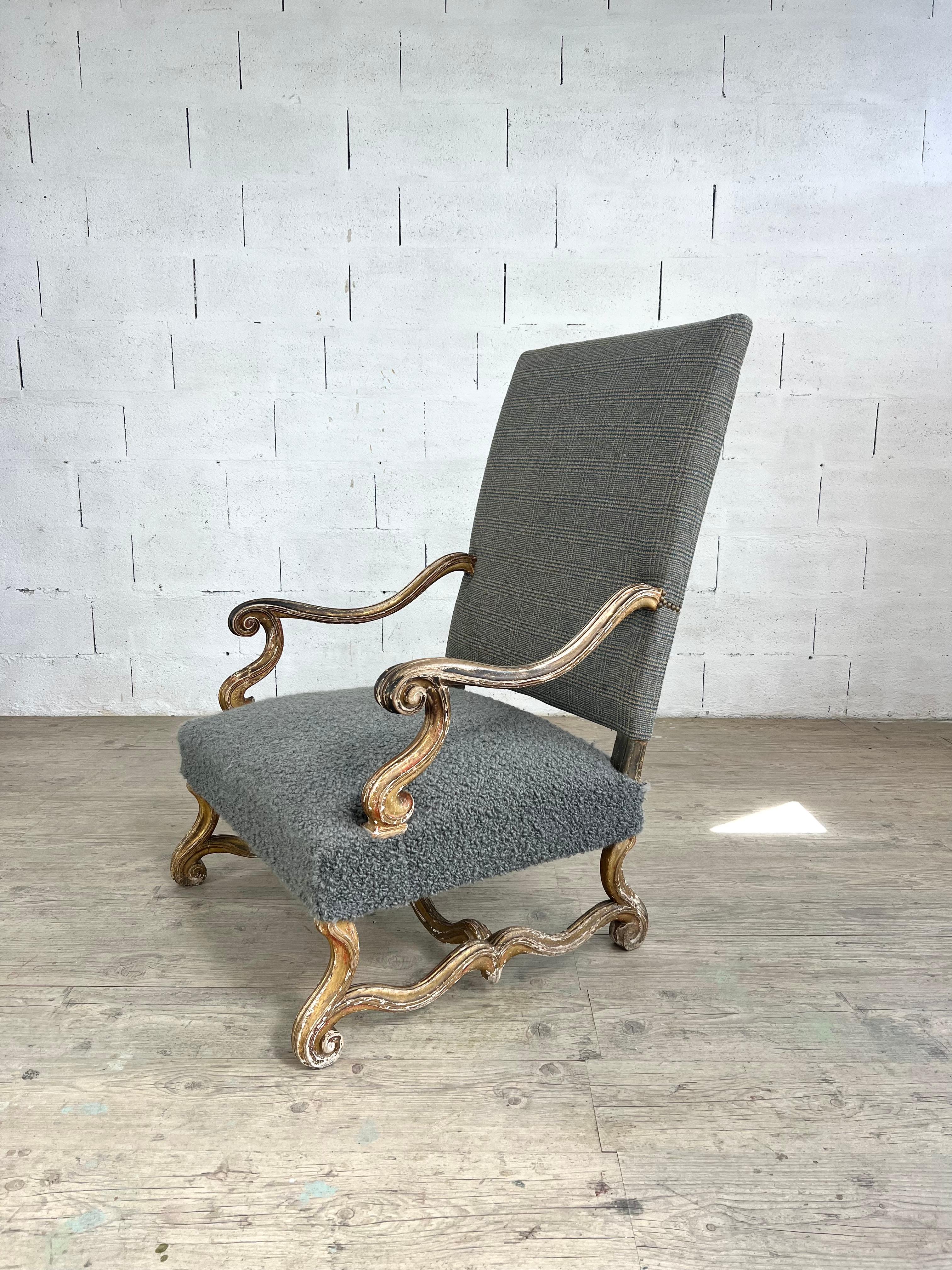 A large 18th-century armchair in carved wood, distinguished by its sculptural presence and refined proportions. The frame is richly shaped with scrolling arms and cabriole legs connected by a serpentine stretcher, all retaining remnants of their
