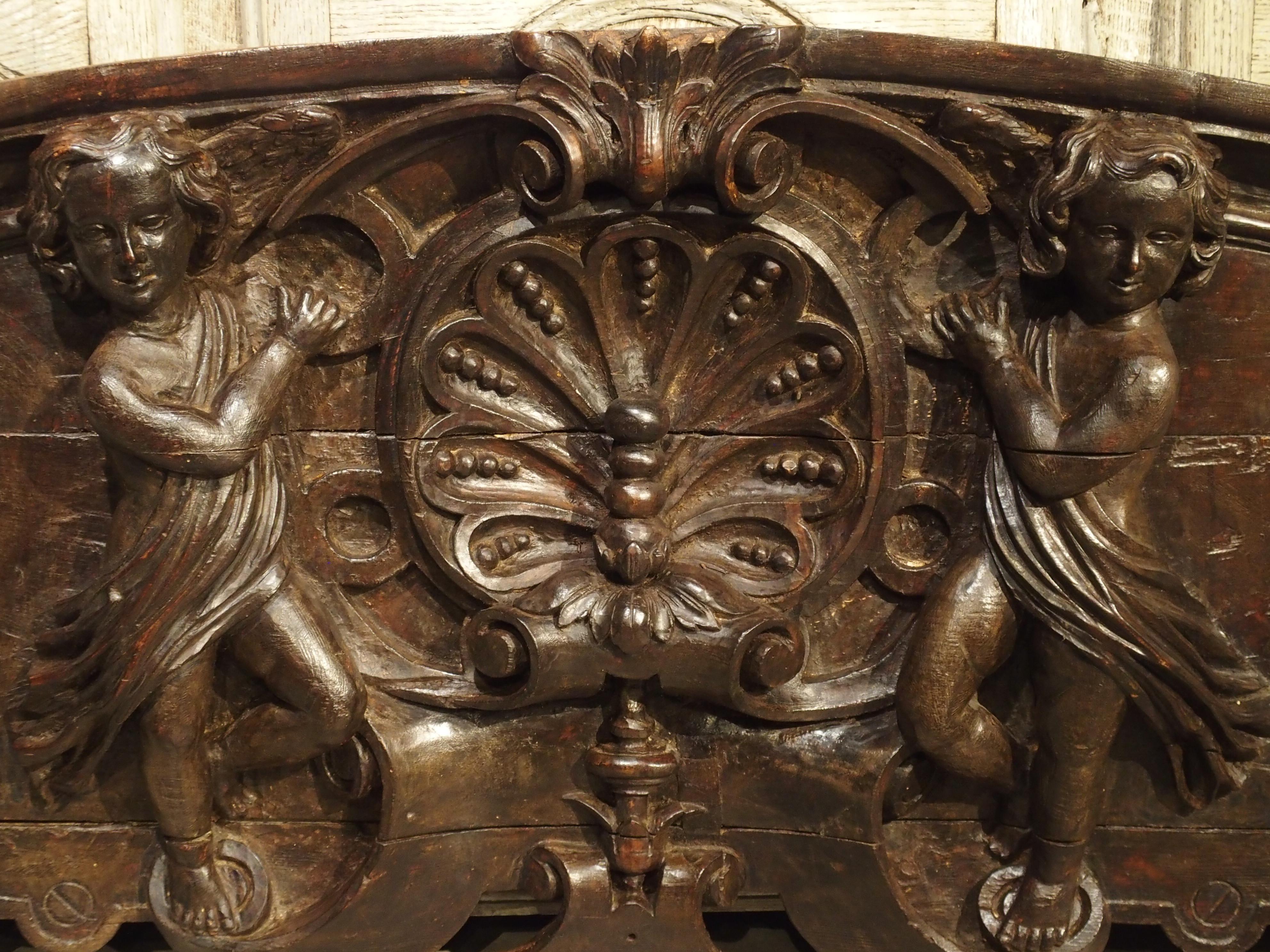 This hand carved wooden overdoor dates to the early 1700s as shown by its main motif at the center. It is called a bat’s wing motif and was used on furniture during the Regence Period, 1700-1723. It is centered within a stylized cartouche, being