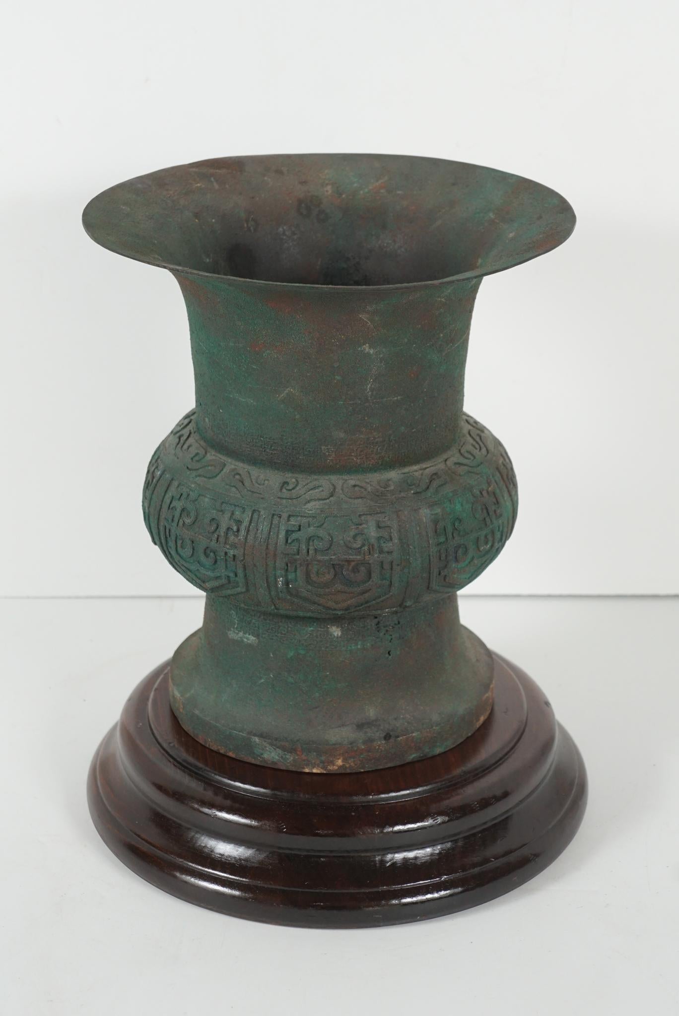 This Chinese cast bronze urn was made to pay honor to the fine vessels produced in the Shang, Zhou and Han periods. This work cast in the late 18th into the early 19th century (circa 1790-1800) has an excellent patina which seems original but could