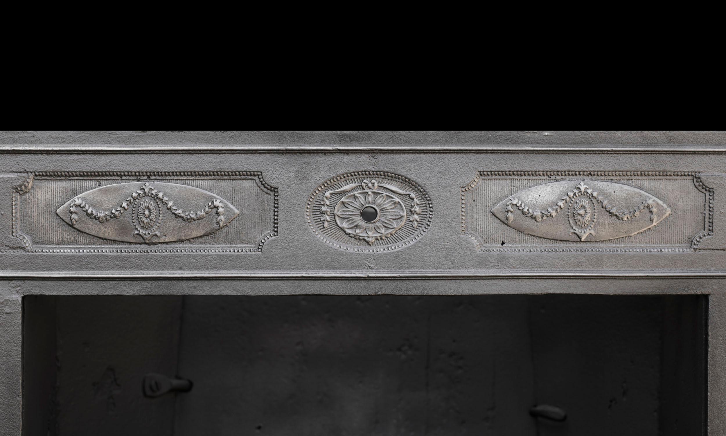 An 18th century cast and wrought iron register grate. The frieze to the outer frame is divided into three panels each containing a swagged oval paterae it is flanked by a pair of fluted columns which are entwined by stylised vines beneath composite