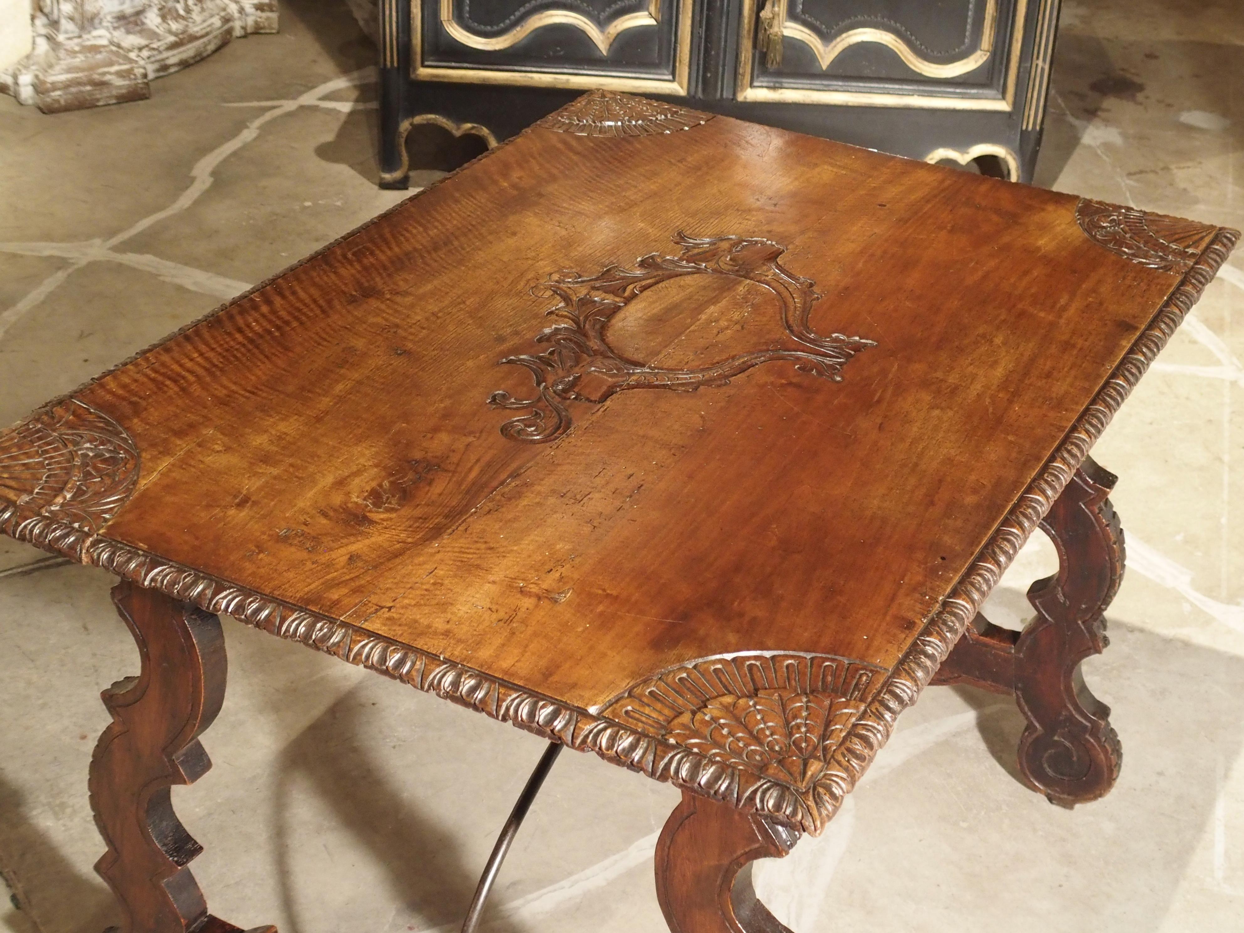 This incredibly unique Catalan table from the 1700s has exquisite motifs carved into its top walnut wood planks. At the center of the table is stylized cartouche with foliate motifs and two demi-figures flanking each side. At each of its four