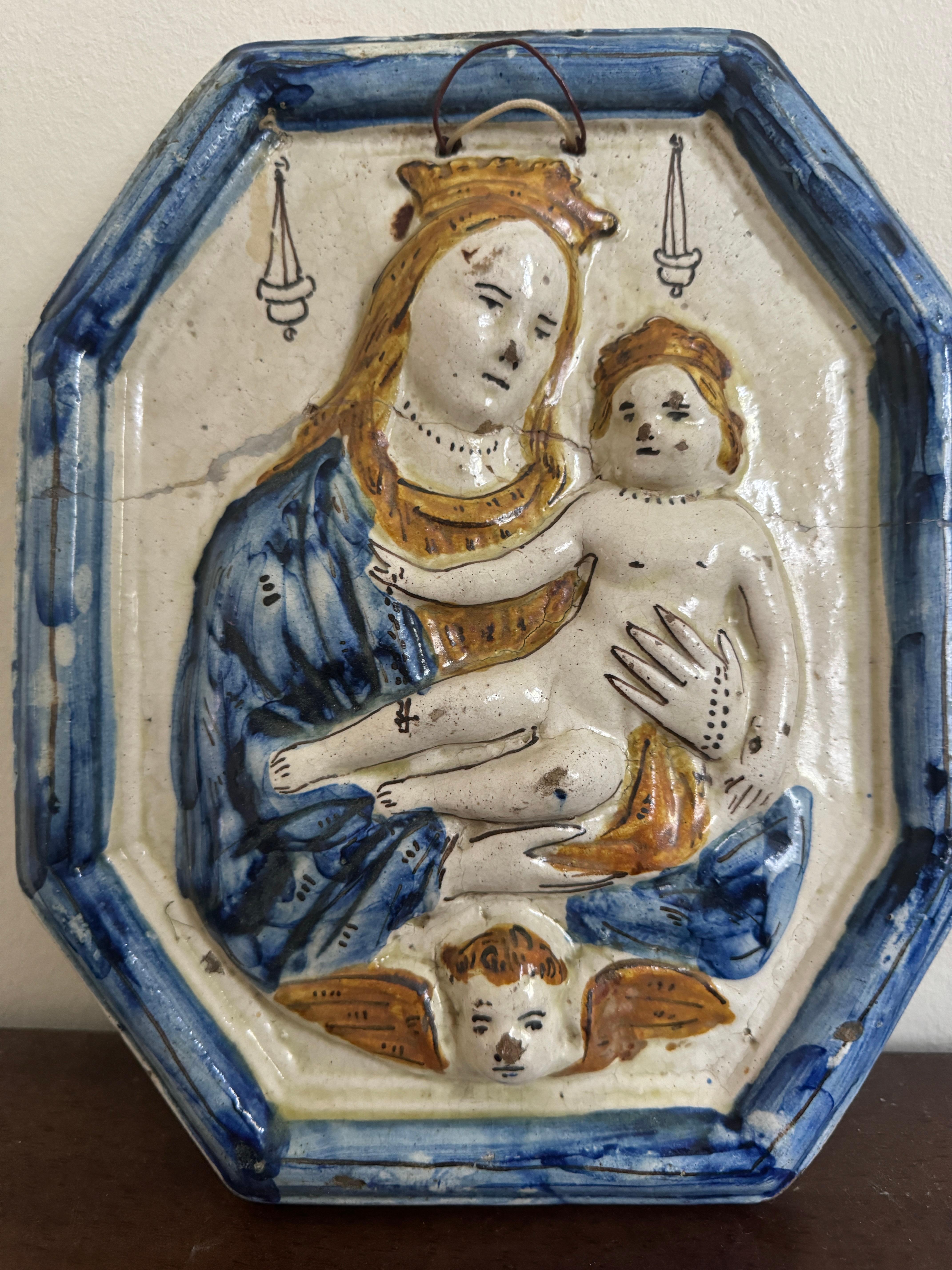 Keramische Andachtstafel aus dem 18. Jahrhundert - Madonna mit Kind, mit polychromen Farben, die die Ränder und die Kleidung verzieren, auch ein Cherub ist am Sockel sichtbar.  Wahrscheinlich wurde er in Spanien oder Italien hergestellt. 