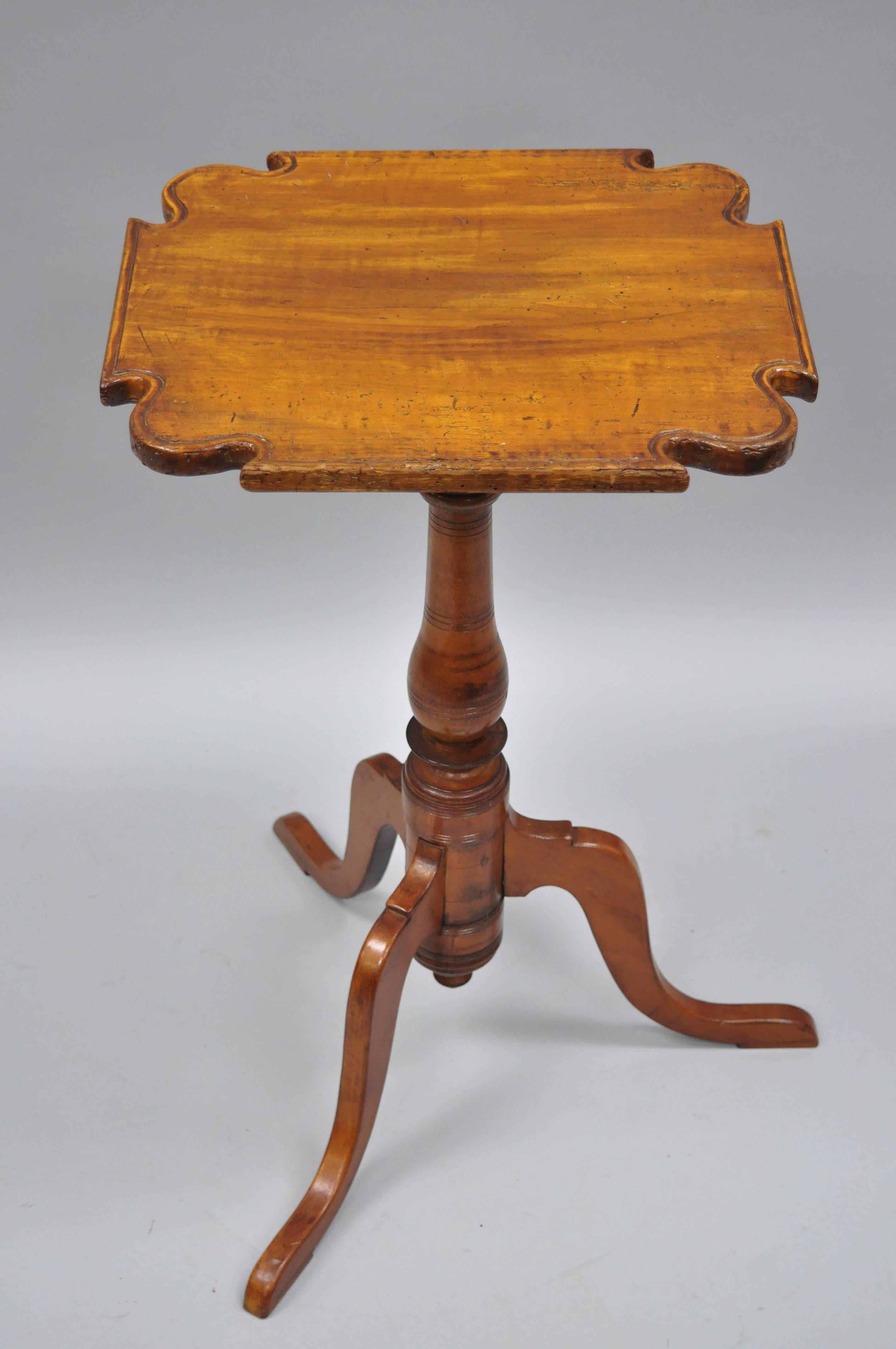 Antique 18th century maple and cheerywood candle stand with tripod pedestal base and scallop carved top. Item features remarkable aged patina and desirable worm holes, tripod base, Queen Anne legs, and carved scallop edge top. Believed to be circa