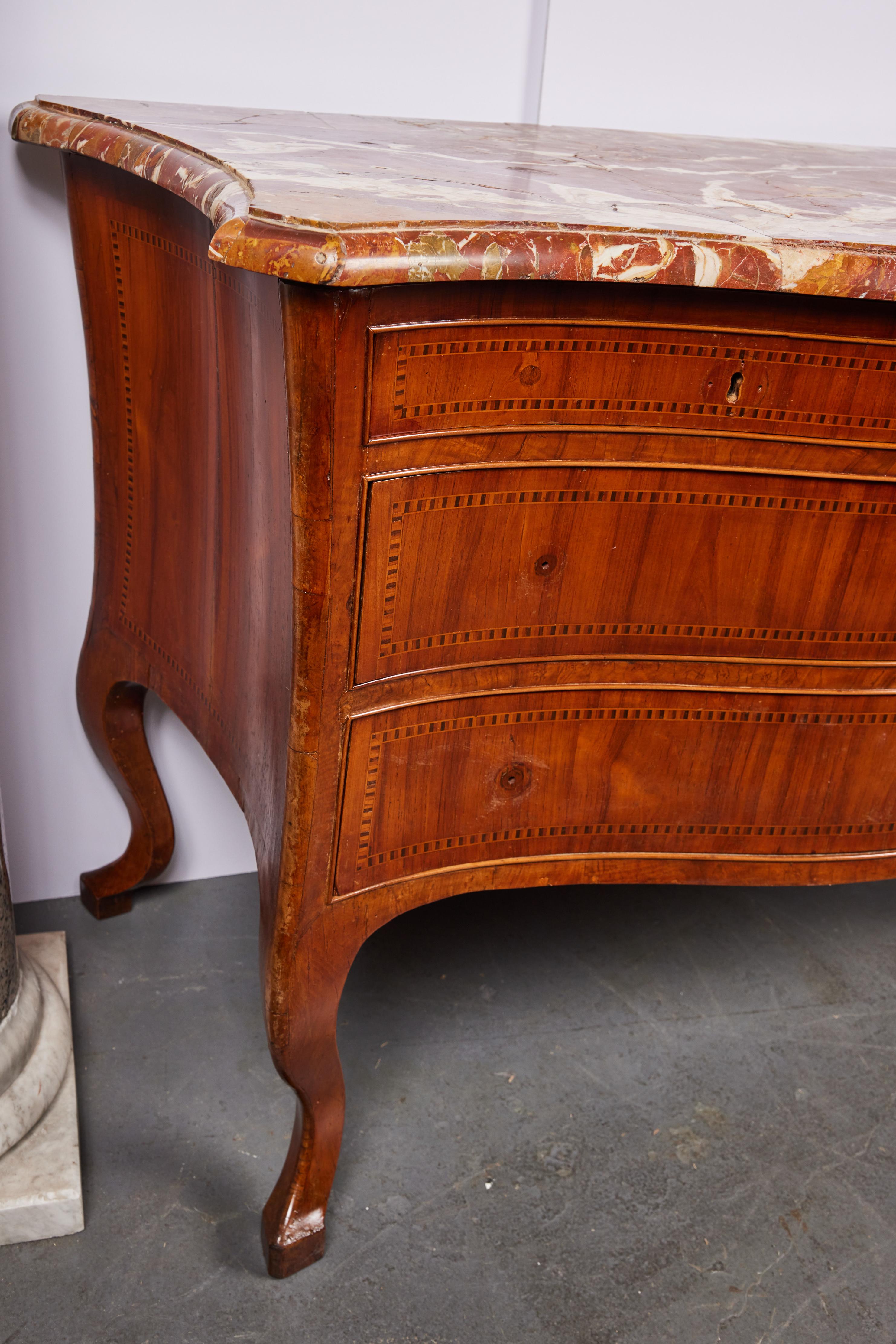 A hand-carved, bow front, serpentine, veneered and inlaid, four drawer commode surmounted by the original, rouge marble top. The whole on wonderful, exaggerated cabriole legs. From the Veneto, Italy.