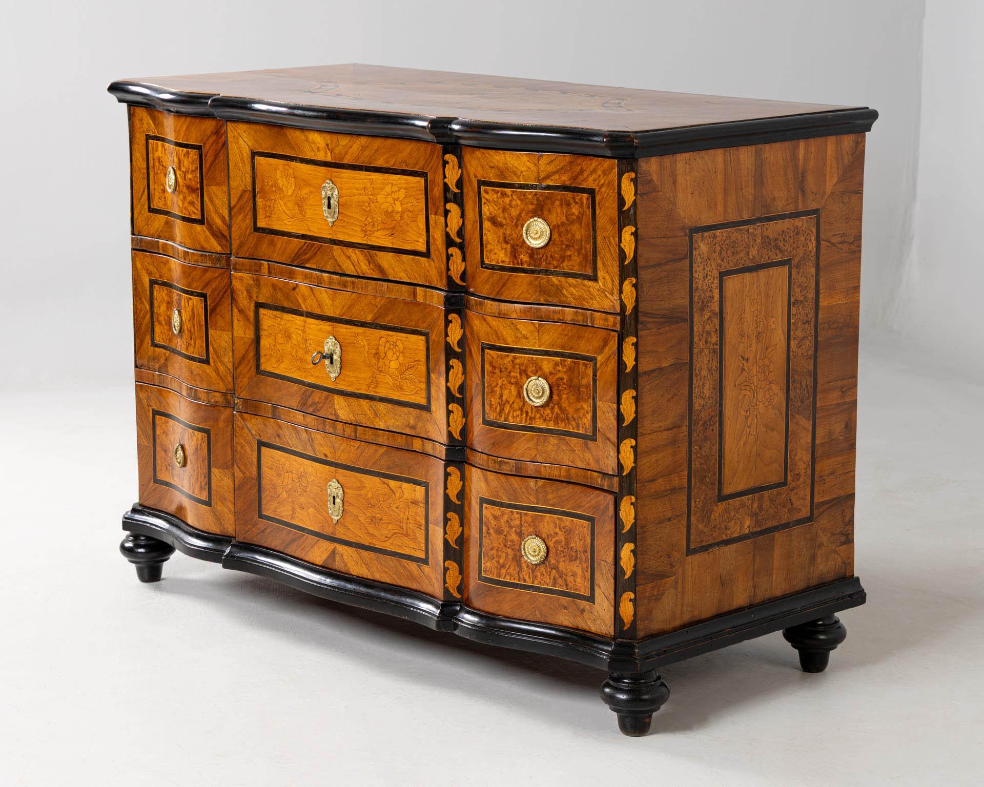 Antike Kommode mit Intarsien

Fulda
Walnuss, Ahorn und andere
um 1785

Abmessungen: H x B x T: 85 x 120 x 57 cm

Beschreibung:
Antike Kommode im typischen Stil von Johann Adam Sauer mit einer noch barocken Form, aber bereits klassizistischen