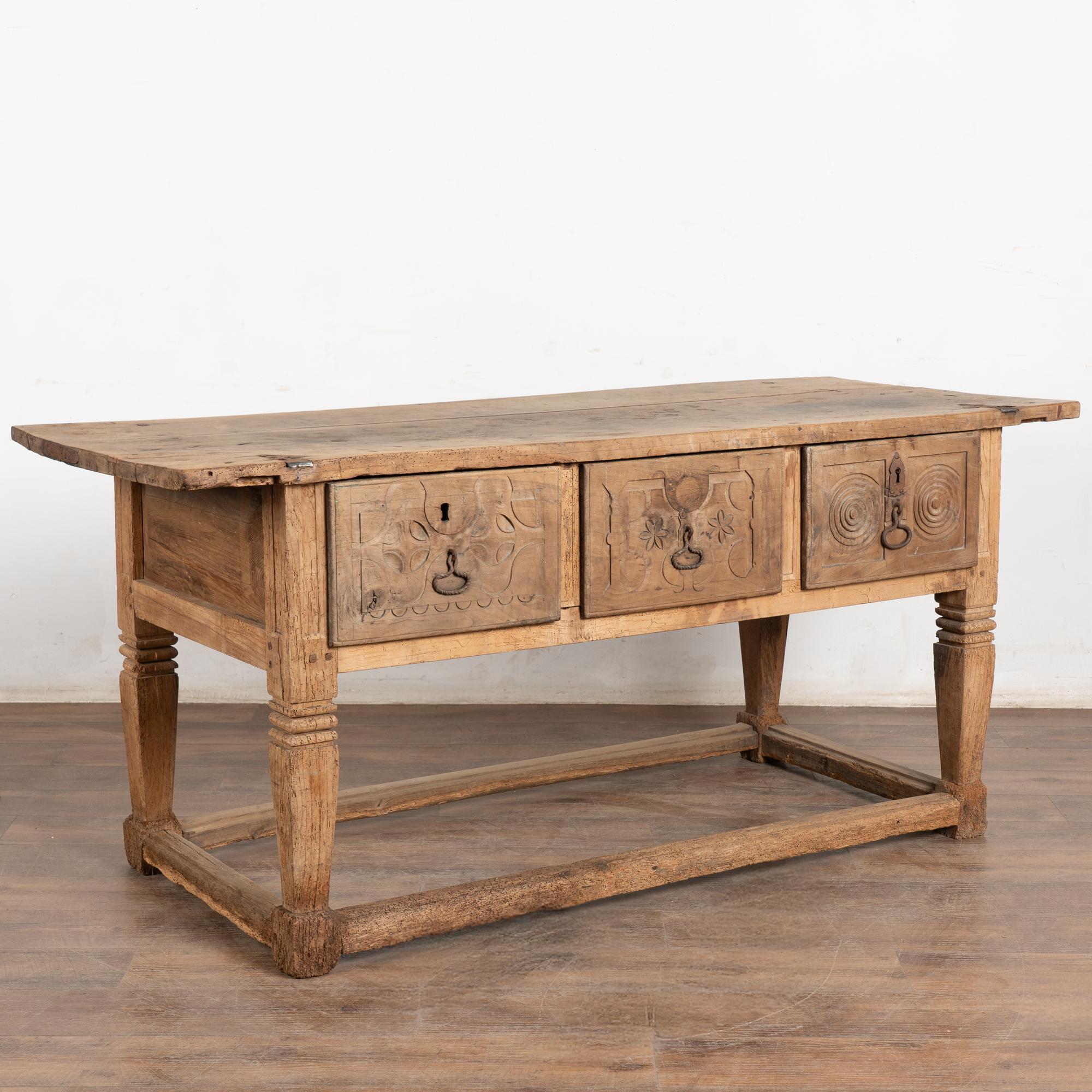 Esta bonita mesa de castaño tiene un atractivo rústico, con tres grandes cajones tallados que descansan sobre una base de camilla.
Consulta las fotos de la parte superior para comprender los años de uso y el deterioro que se aprecia en las grietas,