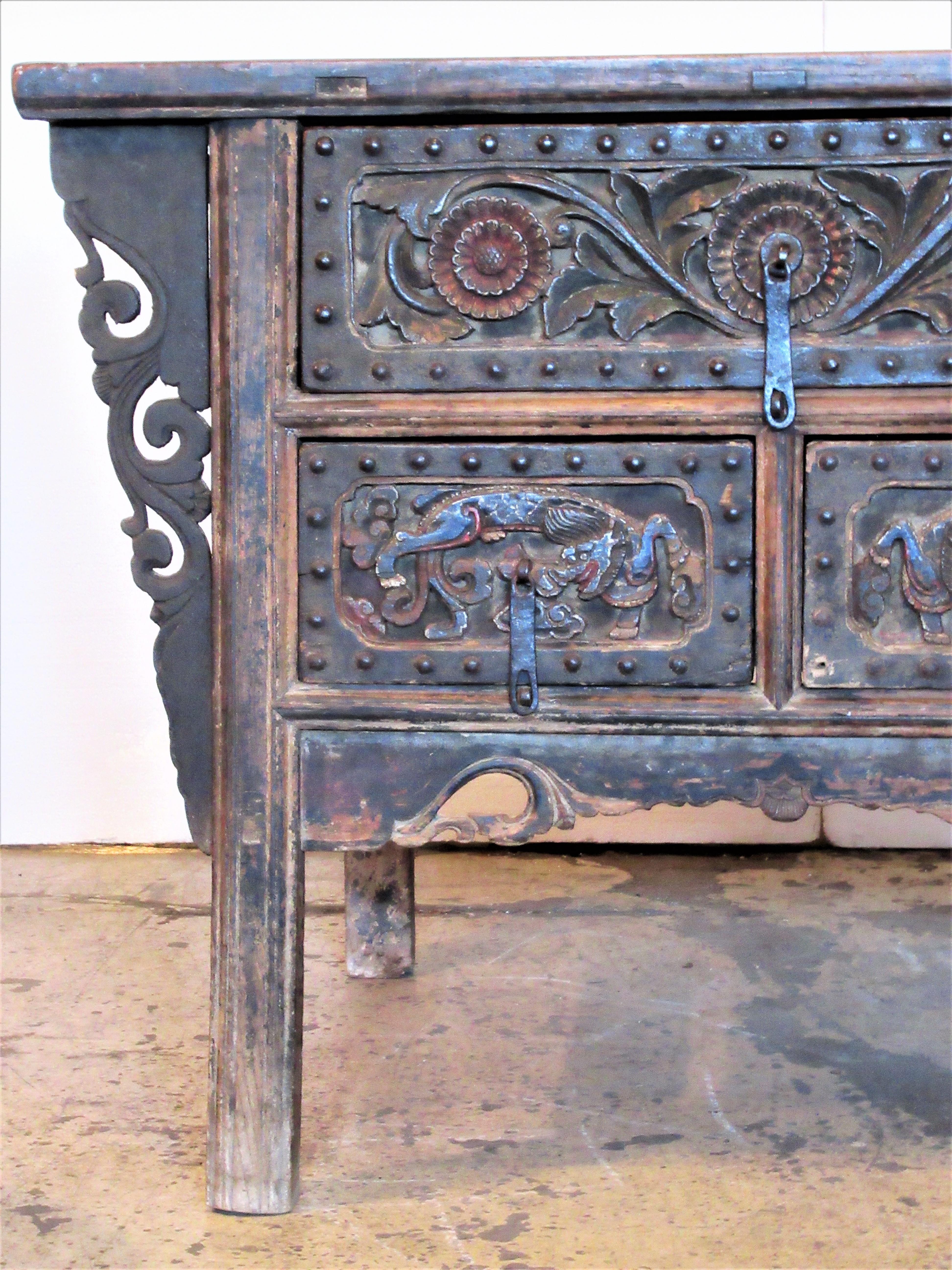 Antique 18th century Chinese hardwood winged altar coffer cabinet with fine bold carvings to the three steel riveted front drawer panels and overall beautifully aged patina color to elm wood and polychrome painted surface. All early case