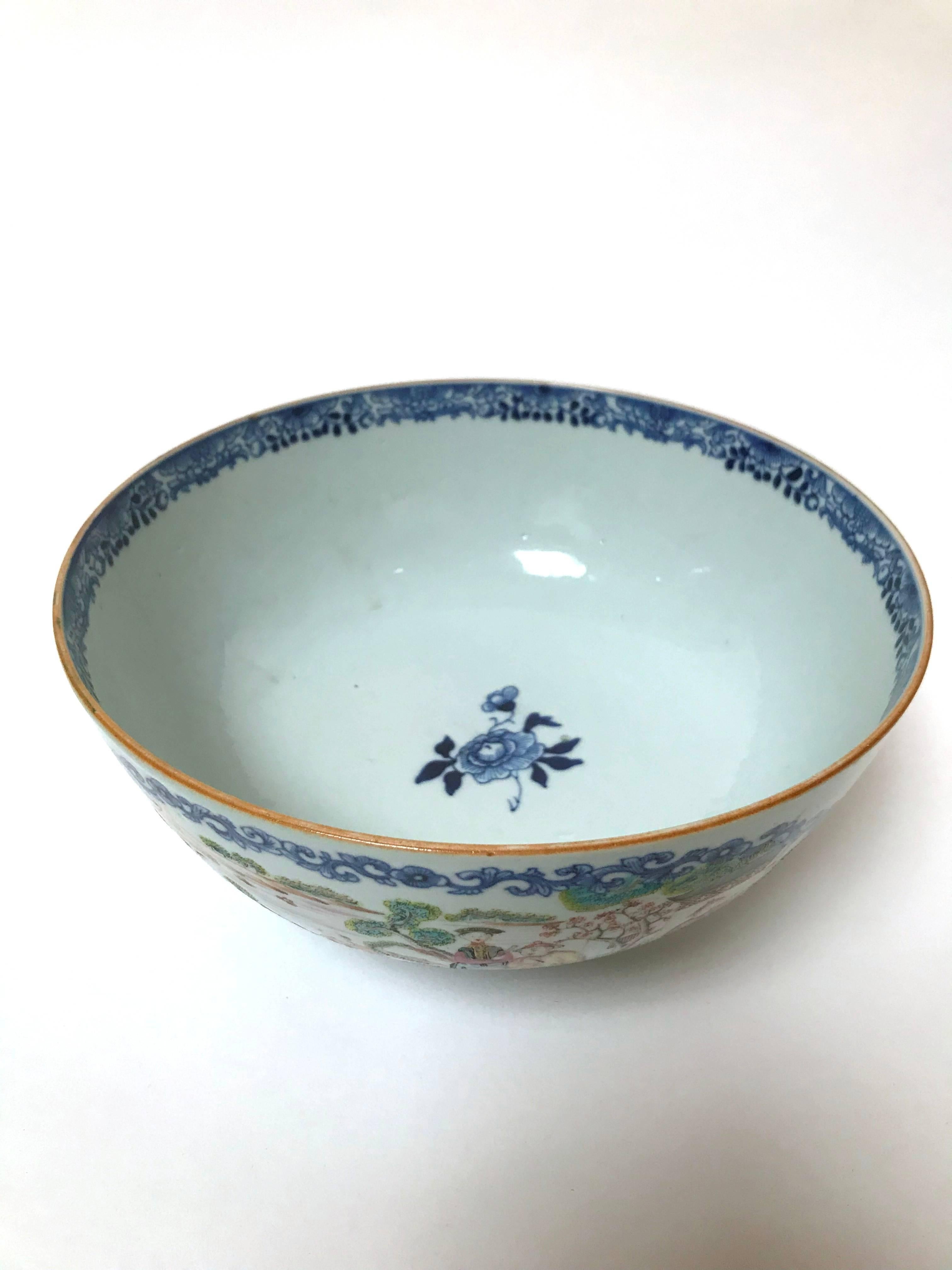 A large centrepiece Chinese Qianlong period export porcelain bowl, circa 1750-1760, painted in polychrome famille rose colors, the exterior with two large opposing panels framed in scrolling foliate forms in underglaze cobalt blue, each panel with a