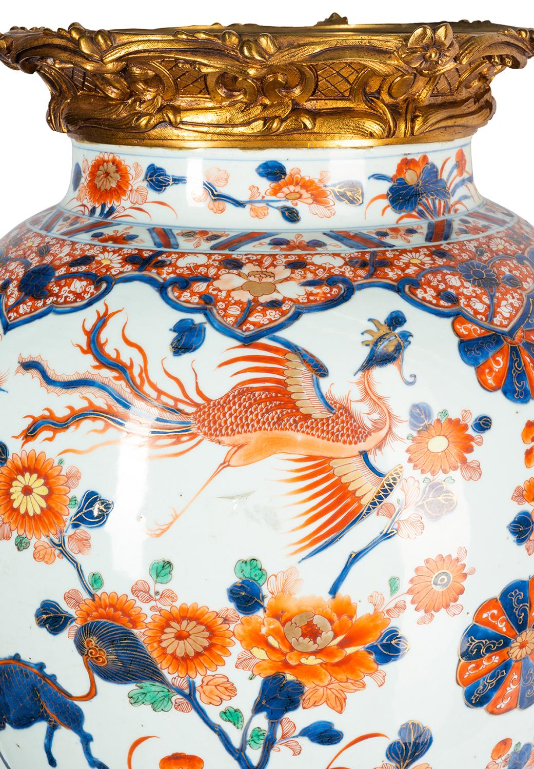 A wonderful early 18th century Chinese Imari lidded vase with fabulous gilded ormolu rococo style scrolling foliate mounts to the neck and stand. The classical hand painted blue and orange Imari colours, depicting various motifs, exotic mythical