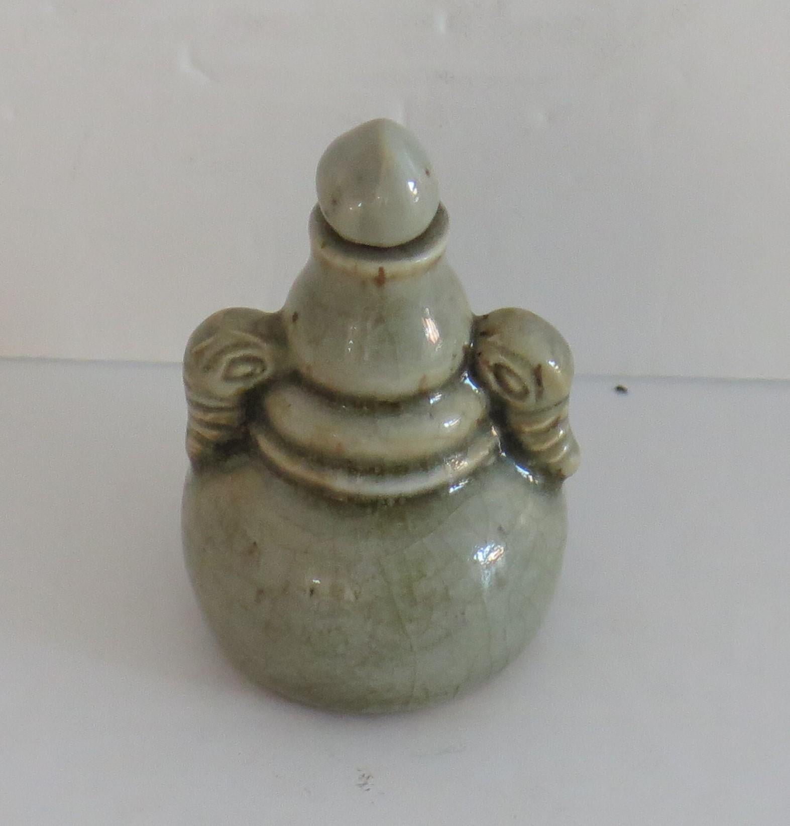 This is a very good quality Chinese porcelain snuff bottle, with a gourd shape and unusual elephant head side handles all in a celadon glaze, dating to the 18th century, Qing dynasty. 

The cylindrical bottle has a single gourd shape with two