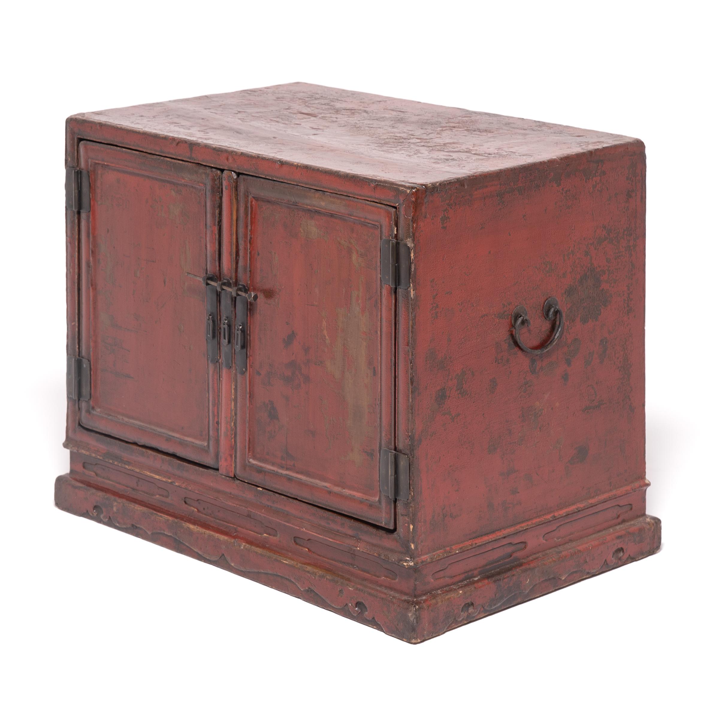 Traces of the original gilt floral painting remain on the doors of this early 18th century red-lacquered chest from Shanxi province. Countless coats of hand-applied red lacquer give the chest its inimitable rich finish. Like many low cabinets from