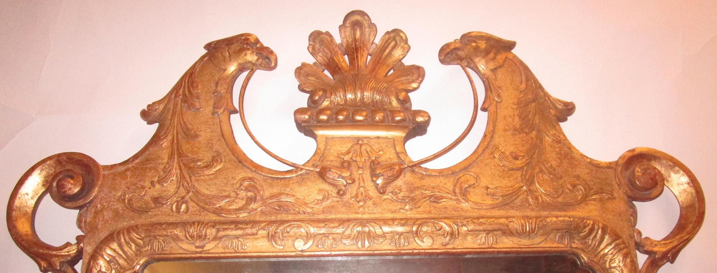 An extraordinary example of an English Chippendale looking glass. The rectangular plate with conforming foliate surround and frame lie beneath a molded swan's neck pediment that features two carved phoenix facing each other and holding delicate