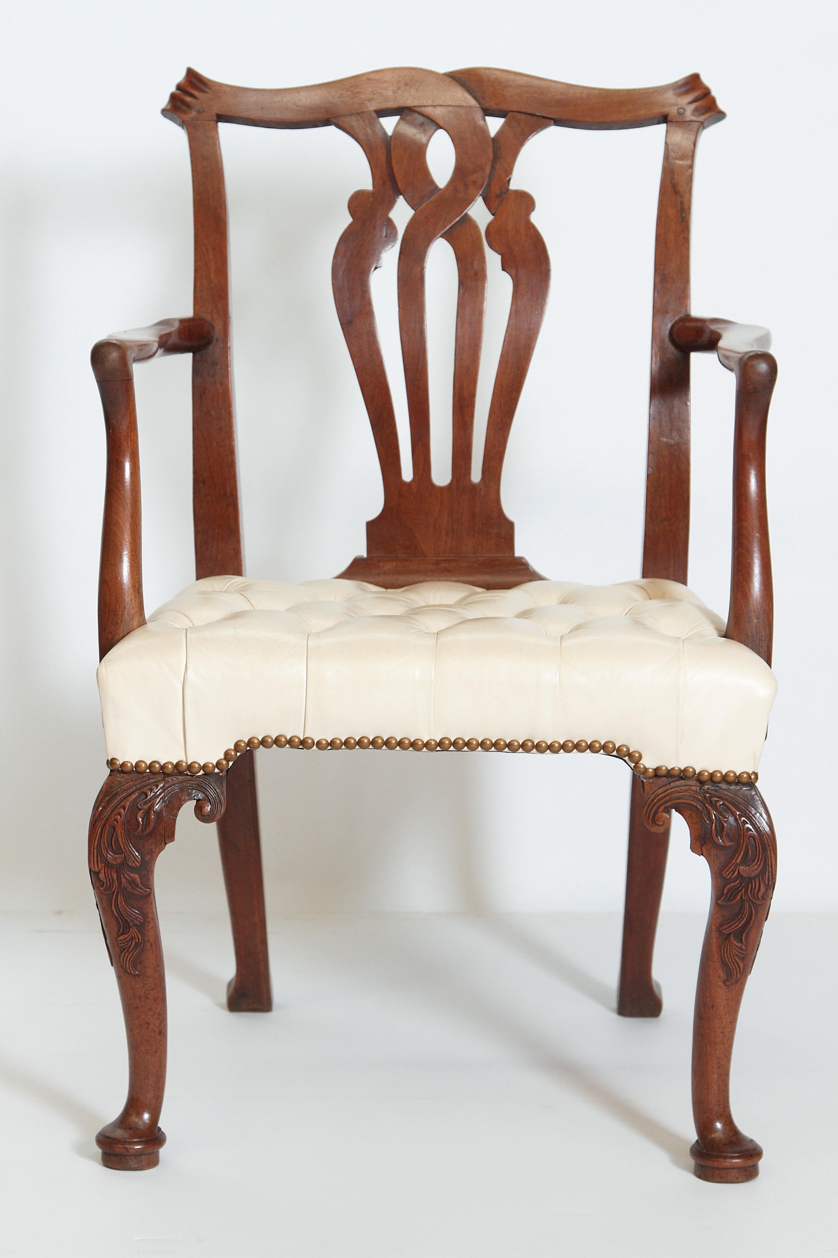 An early George III Chippendale armchair with tufted off-white leather seat. Serpentine crest rail ending with scrolled ears. Pierced splat back with curving arms above a nicely carved knee on cabriole front legs on pad feet, 18th century, England.