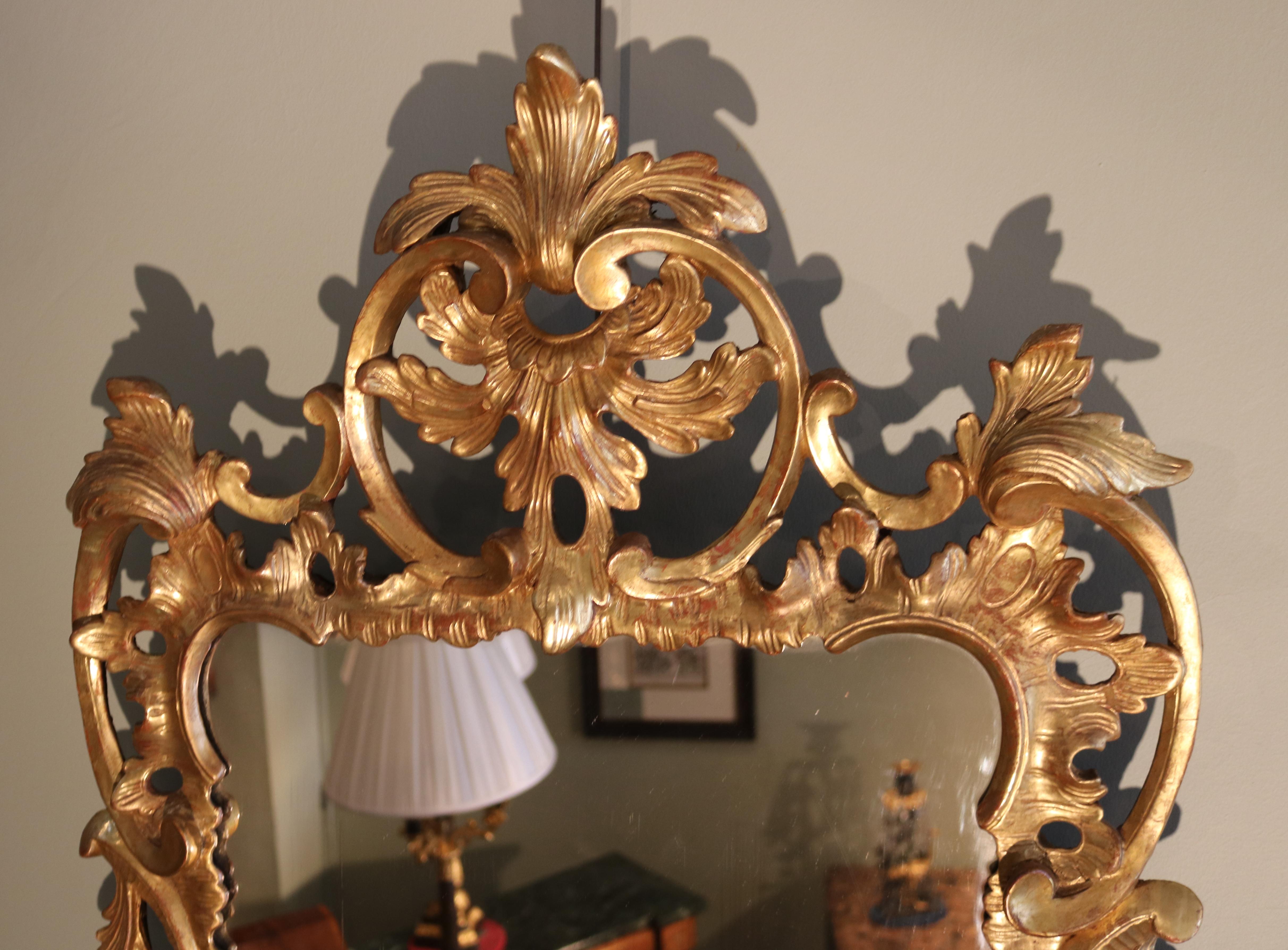 A mid-18th century Chippendale period mirror, of attractive small proportions, boldly carved throughout with c-scrolls, acanthus leaves and fruit and flowers, having cartouche decorated top and bottom.