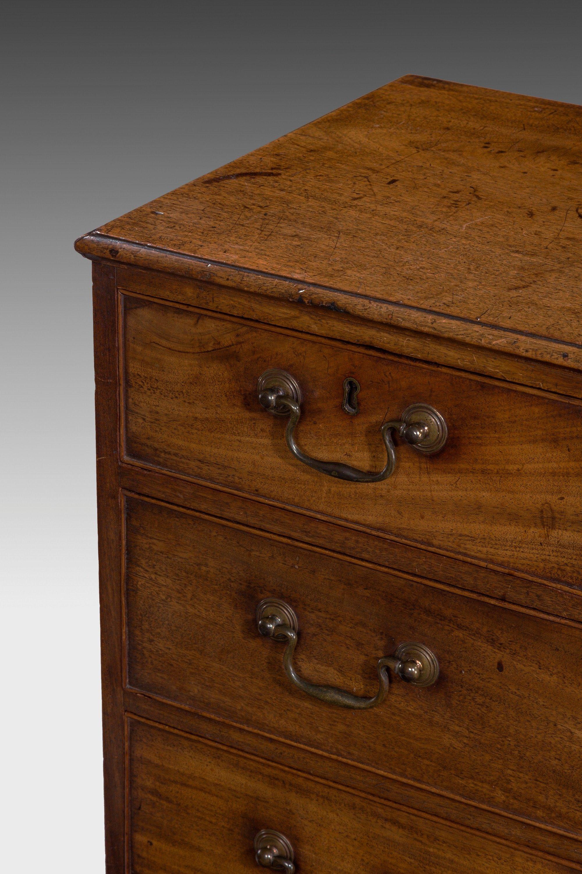 This lovely George III period mahogany chest of drawers is of elegant tall and narrow proportions and glowing warm color, with two over three graduated drawers retaining the original brassware, all on unusual shaped bracket feet. ¬†.