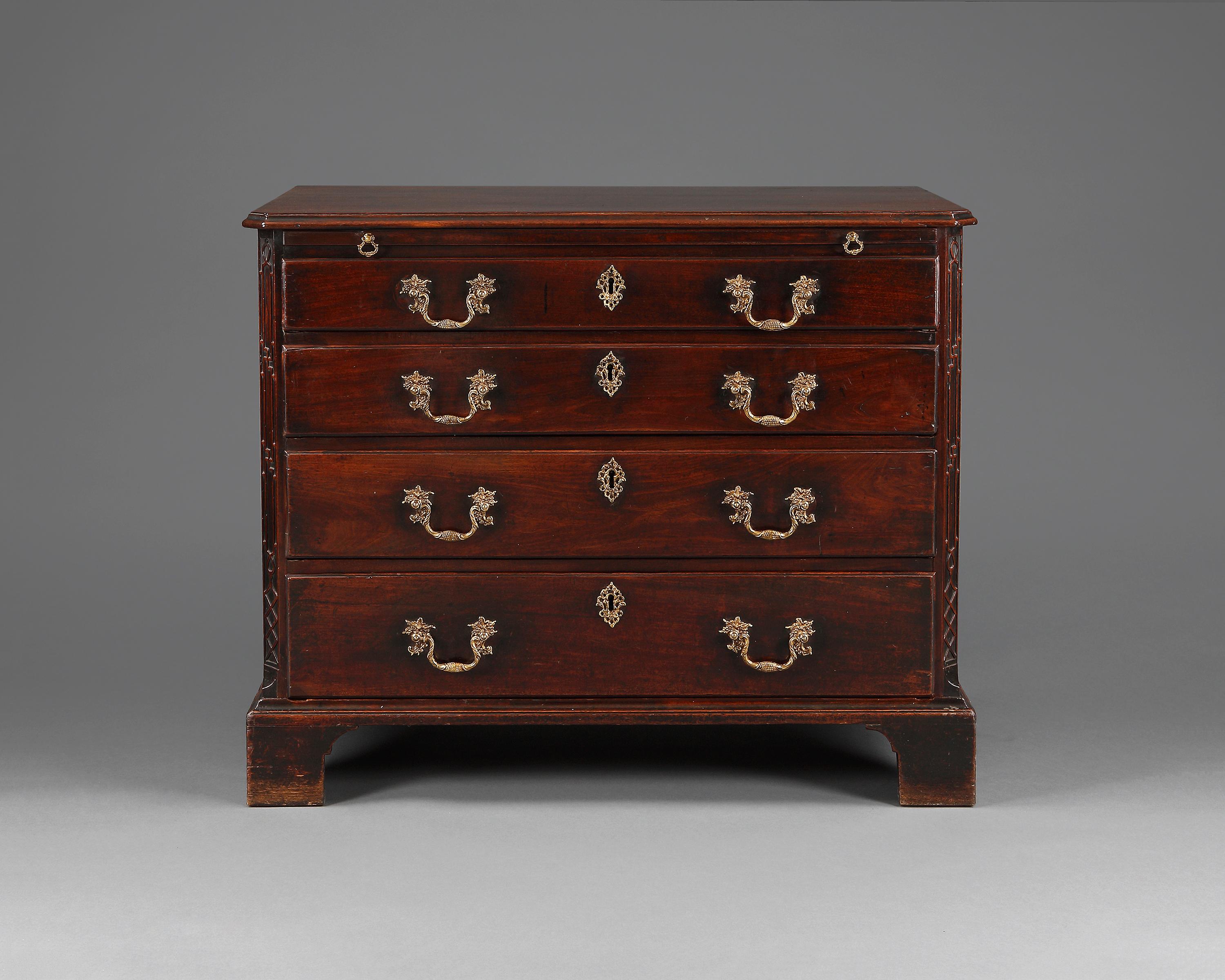A fine Chippendale period mahogany chest of drawers. The rectangular moulded top above a brushing slide with four long graduated oak lined drawers below. The cantered ends having blind fret-work decoration. The whole is raised on the original