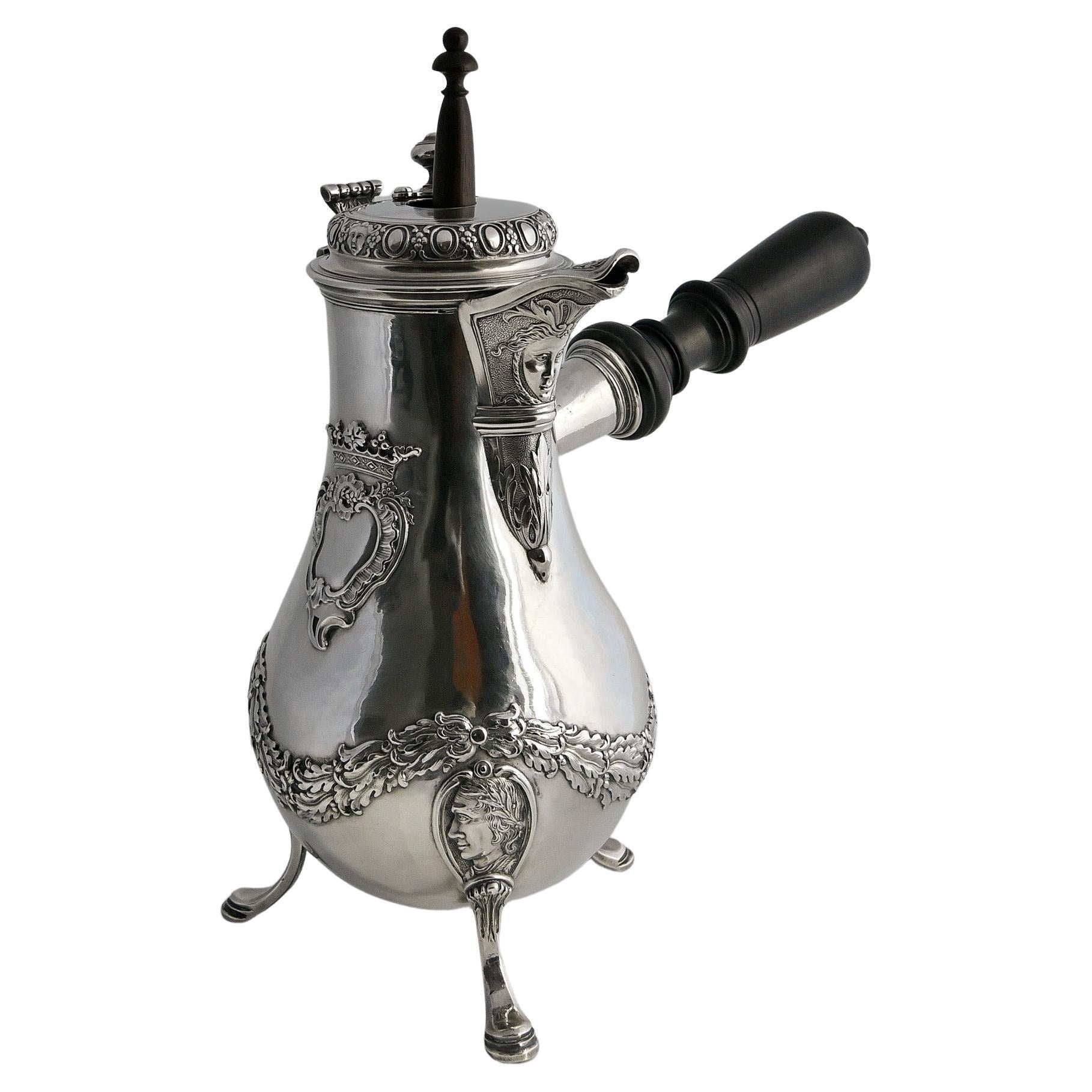 Chocolatiere in solid silver. Silver content 950. 
Particularly beautiful molding on three feet, wall with garland decoration, fine potrait medallions on the legs and elaborated heraldic cartouche. The wooden handle can be unscrewed and also has a