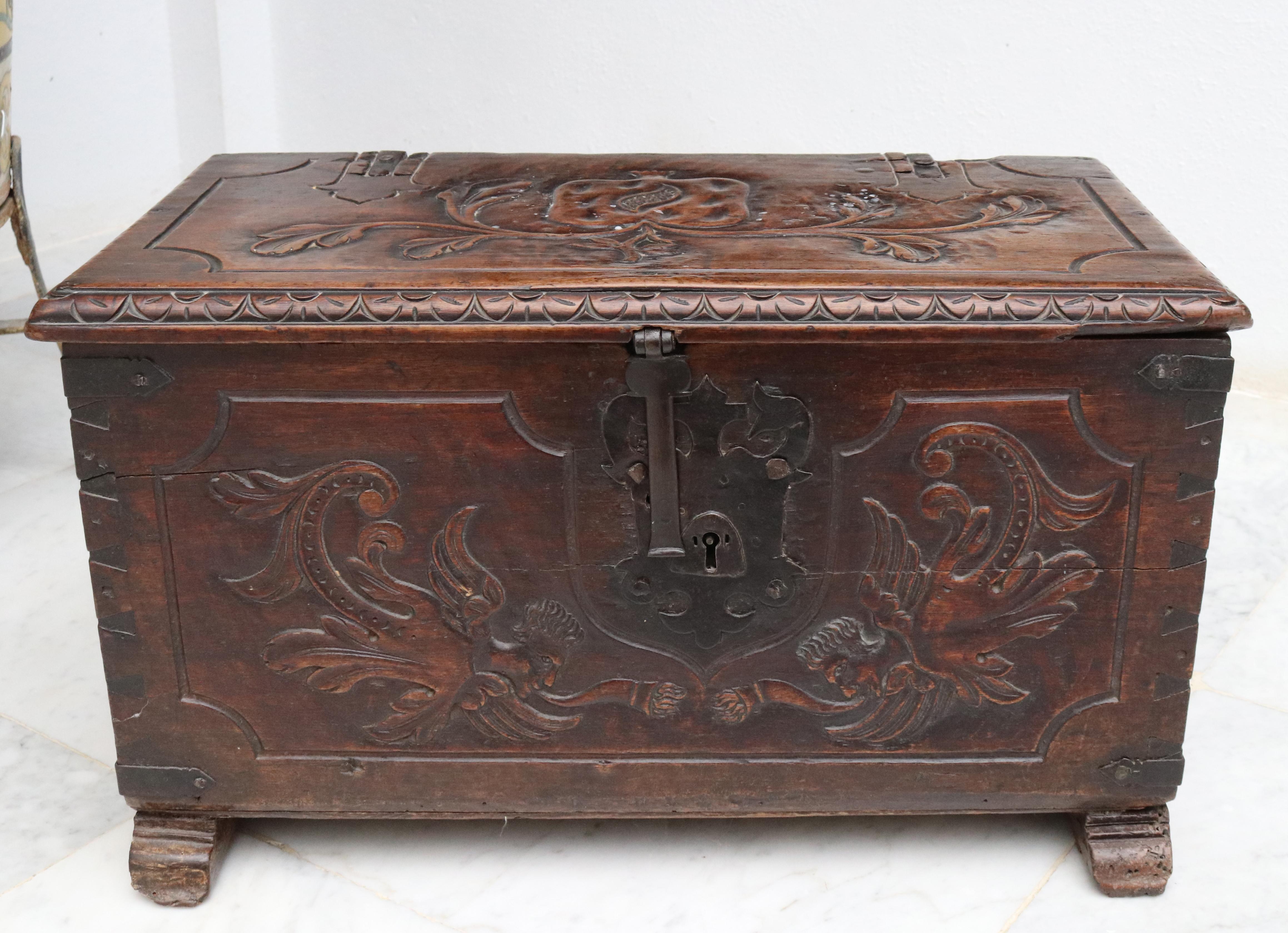 18th century colonial wooden trunk with hand carved ornamental, flower and bust reliefs on top and sides. Wrought iron fittings, decorations and side handles.
 