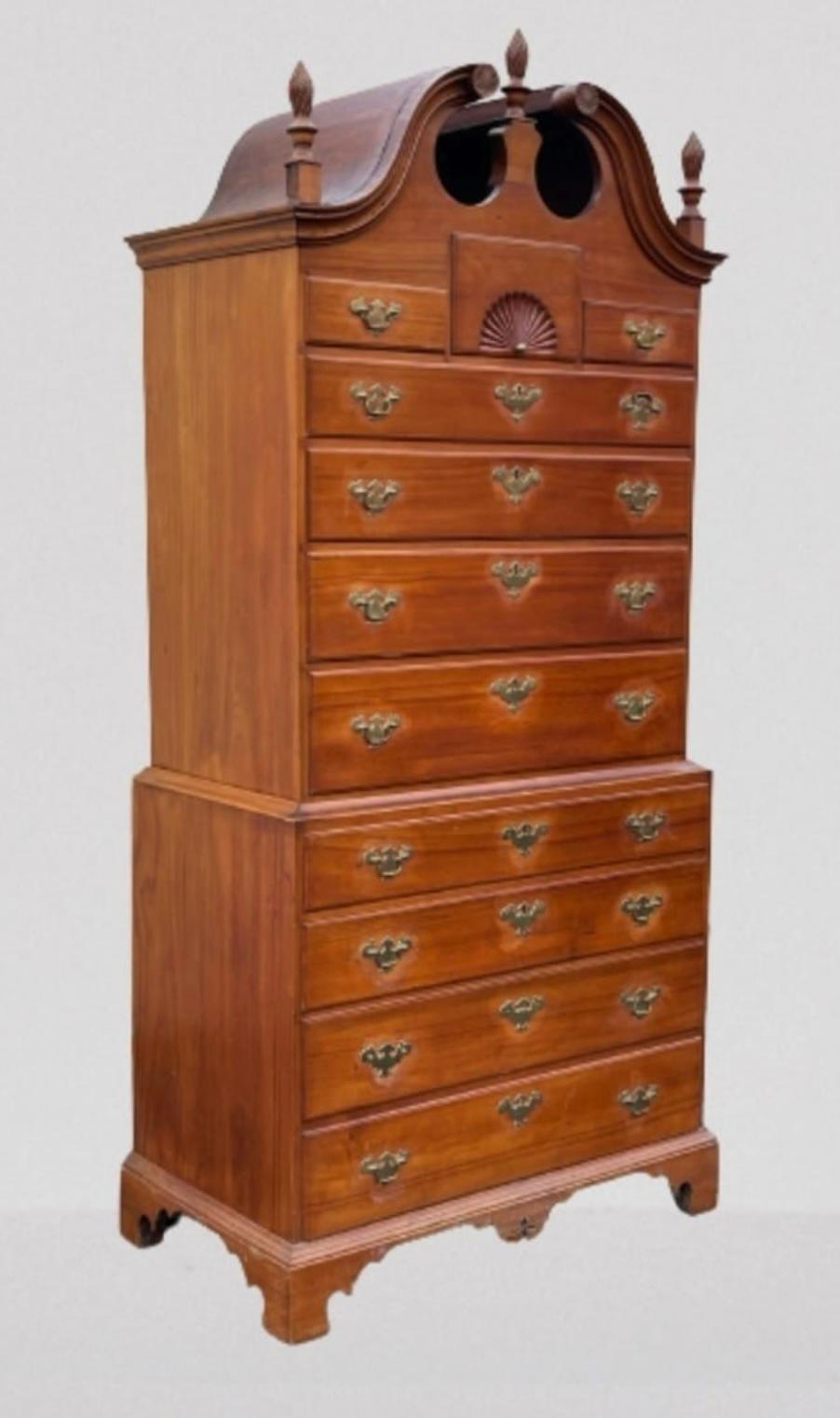 A fine example of an 18th century Connecticut chest-on-chest in Cherry with a bonnet top and flame finials, over three small drawers, the center with a carved fan, over 7 full length drawers (the lowest being a double depth drawer) all retaining