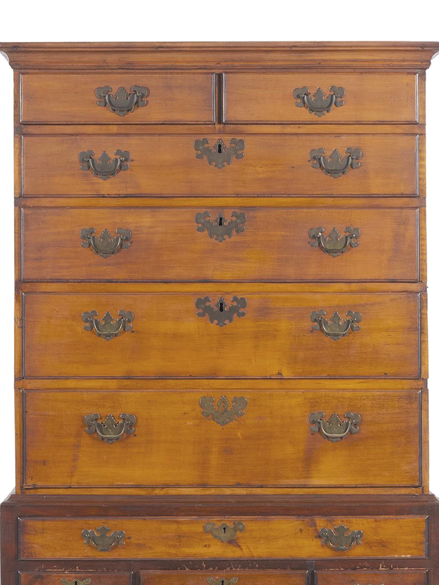 An 18th century highboy in the Connecticut Queen Anne style. The highboy is expertly crafted from cherry wood. It's comprised of two case pieces. The top segment is a flattop with 2 small drawers and 4 full length drawers. The bottom segment has 4