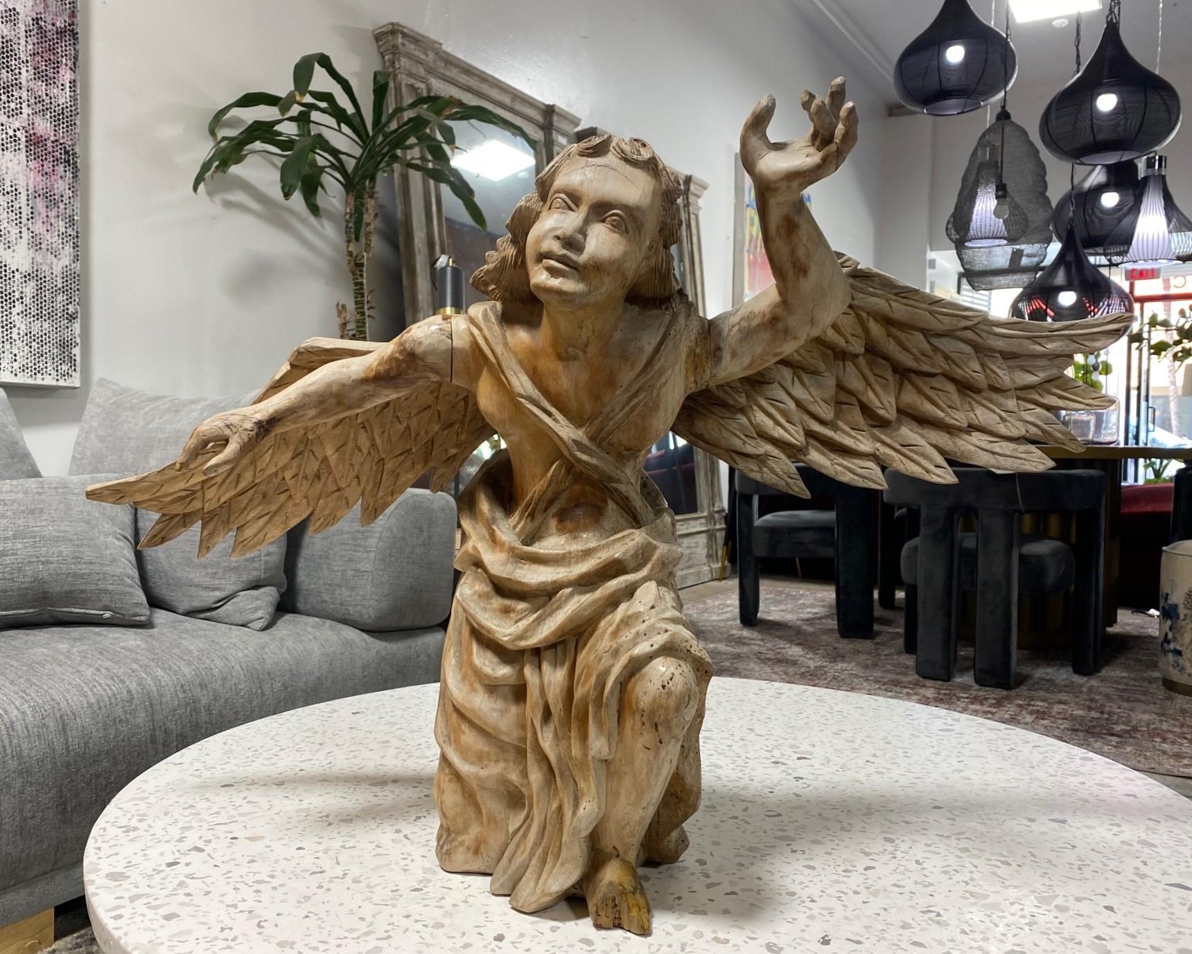 A truly magnificent and wonderful large hand-carved Italian Baroque wood church angel from the 18th Century. This work, which at one point was likely polychrome and painted, features a finely carved kneeling angel gazing at and reaching for the