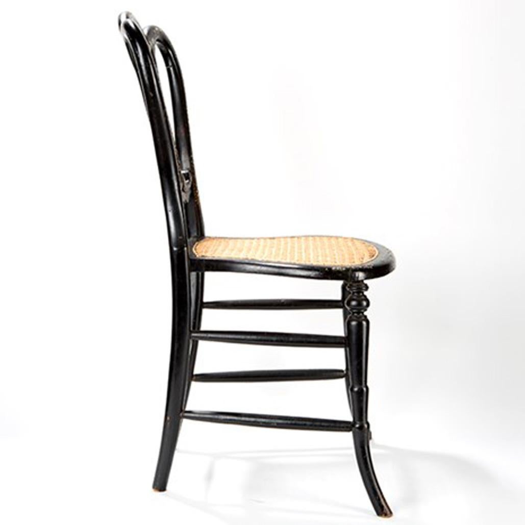 This chair made of ebonised wood captivates with its fine mother-of-pearl inlays and the elegantly curved backrest. The legs and the backrest are decorated with very fine gold paintings, which are particularly striking because of the dark