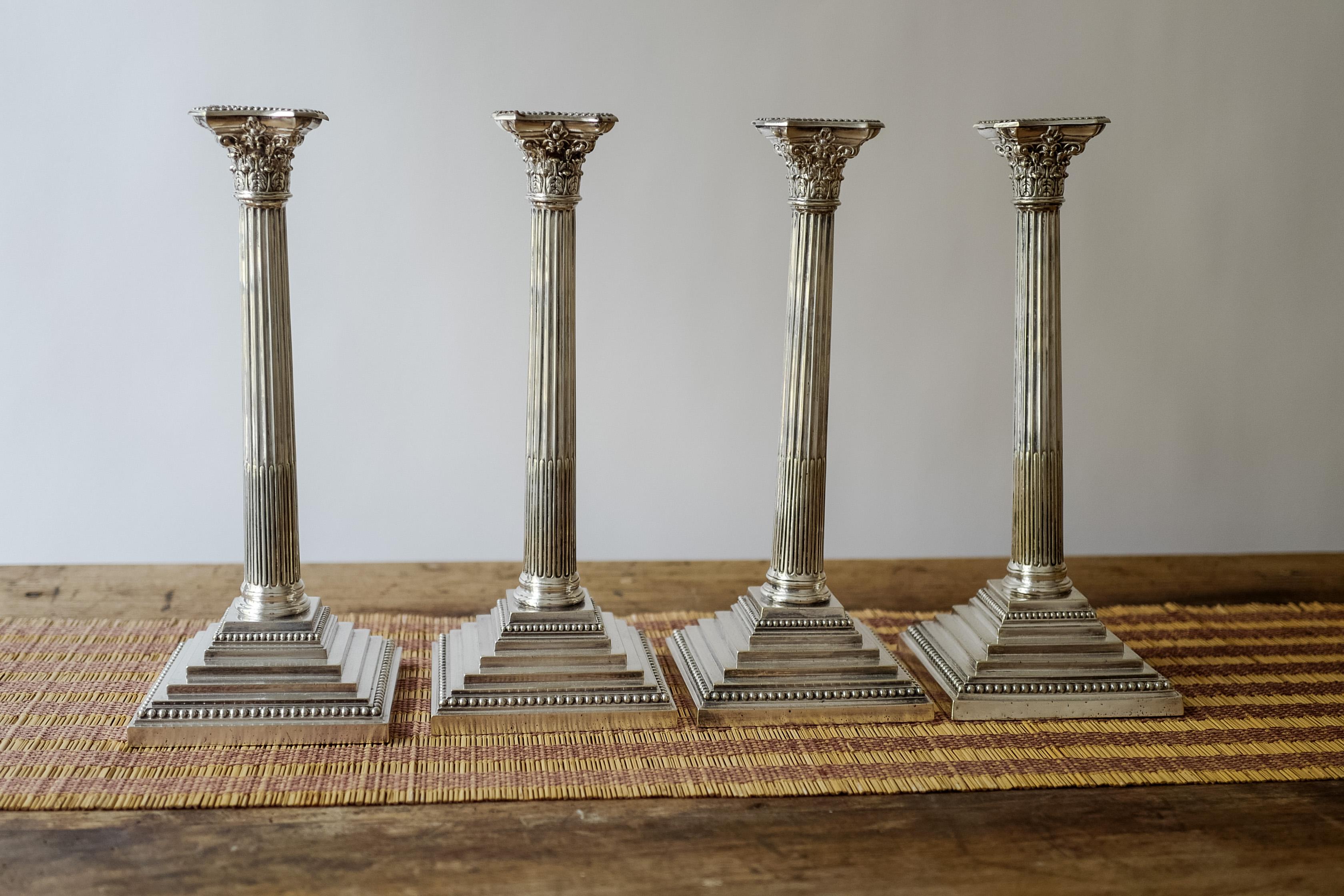 A set of four Richard Hodd and Son sterling silver Corinthian English candlesticks circa 18th century. Acanthus decorated sconces with scroll supports Silver beading to sconces and platforms. Terraced pedestal bases shaped wax pans and removable