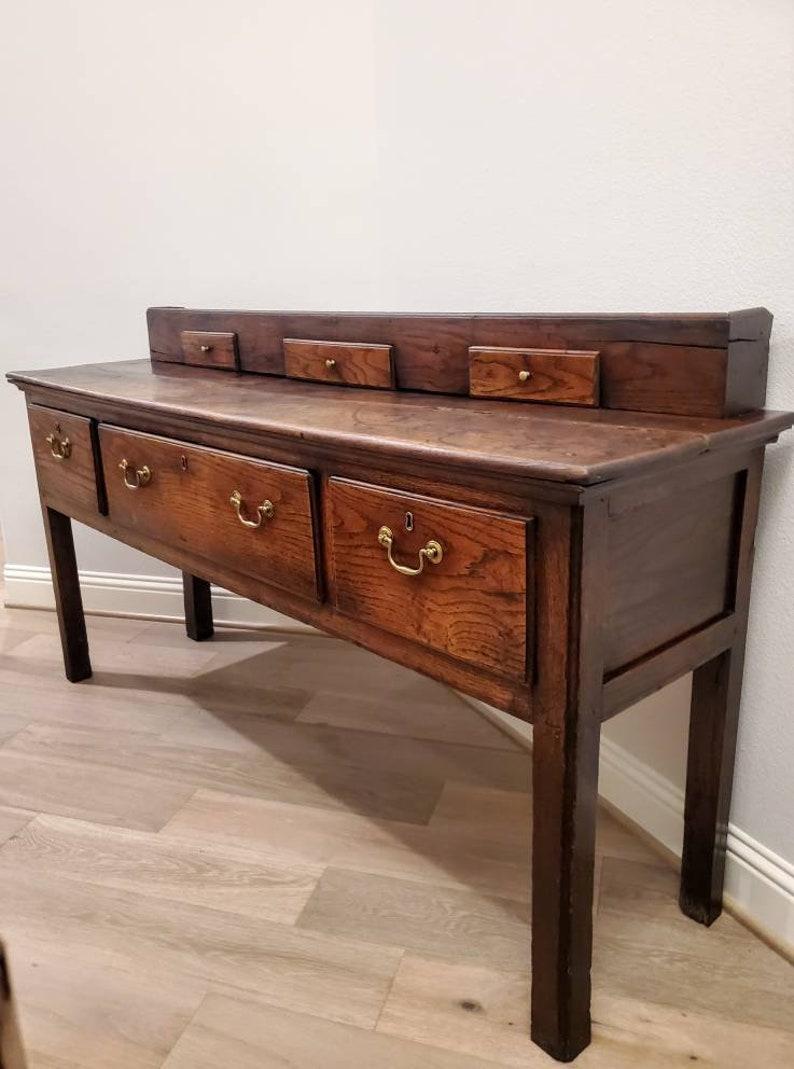 An antique, circa 1780, country English chestnut long table with rich beautifully aged patina. 

Born in England in the 18th century, Welsh dresser base form, featuring a thick plank top with desirable overhang, a later raised gallery having three