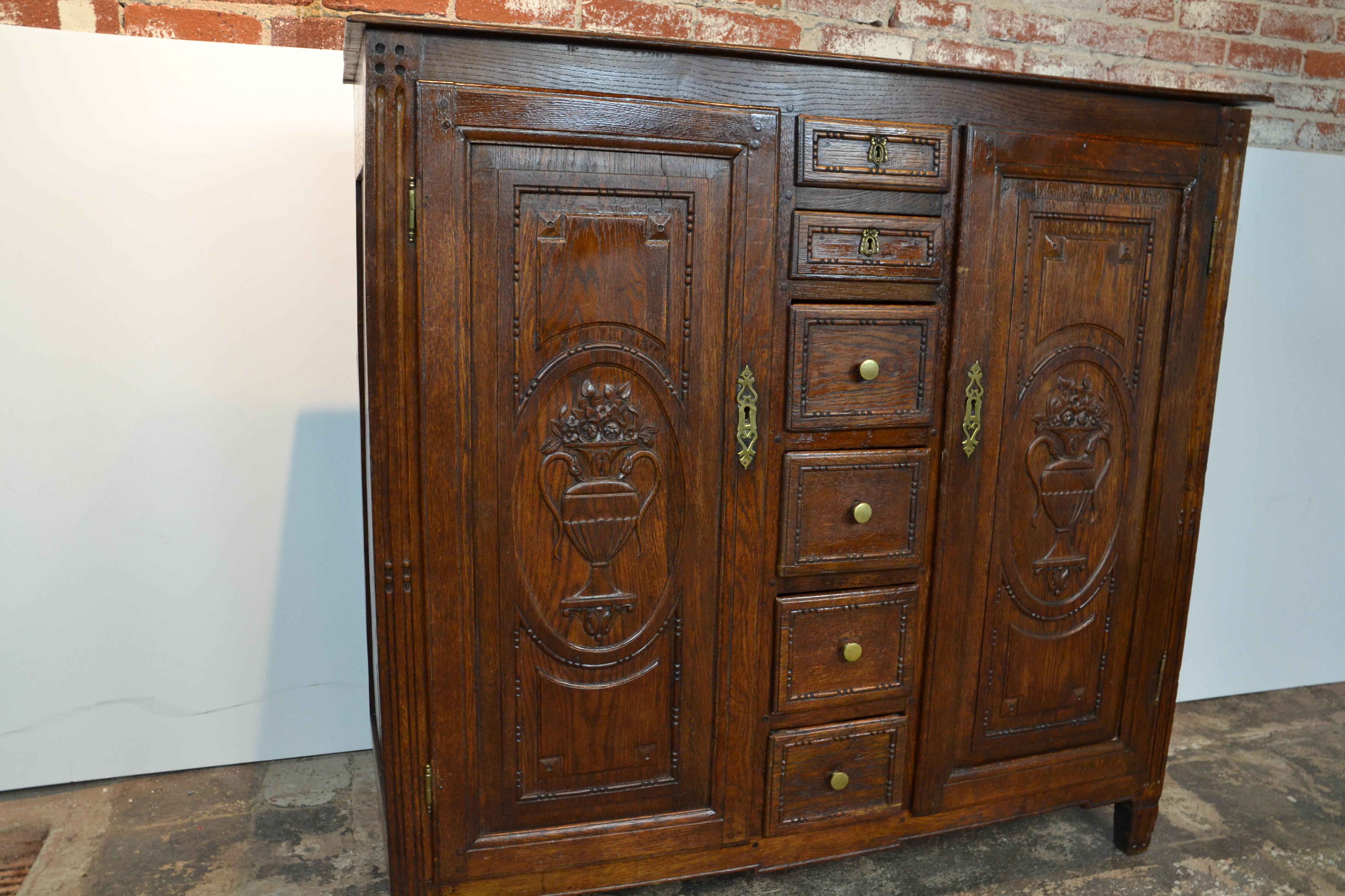 Un armadio provinciale francese con armadi e cassetti. Porte decorate con urne floreali. Design a perline intorno alle porte e ai cassetti. Ferramenta in ottone, varie vecchie etichette sul retro, circa 1780.
