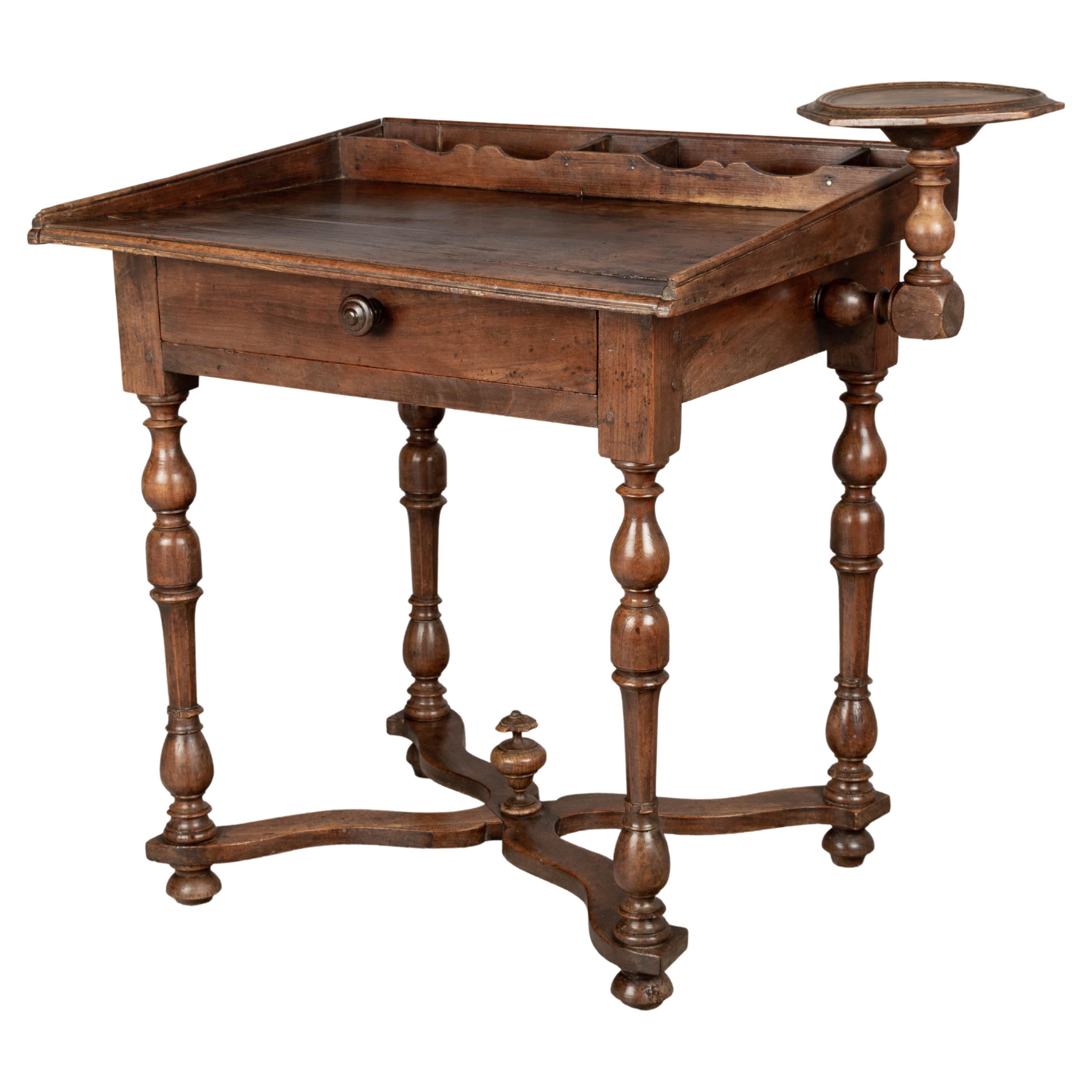 A late 18th century Country French child size desk, made of solid cherry. Beautifully crafted with turned legs and carved stretcher with center finial. Candle stand on the right, attached with turned peg. Missing the candle stand on the left.