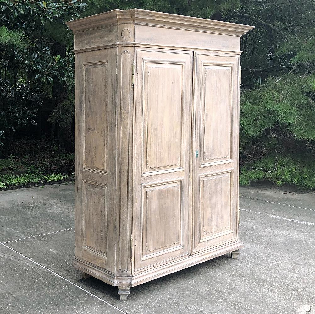 18th century Country French Louis XIV Whitewashed armoire lends a stately presence wherever it may be placed! Bold crown molding with recessed, mitered corners presides over the spacious raised panels below, with special attention made to the corner