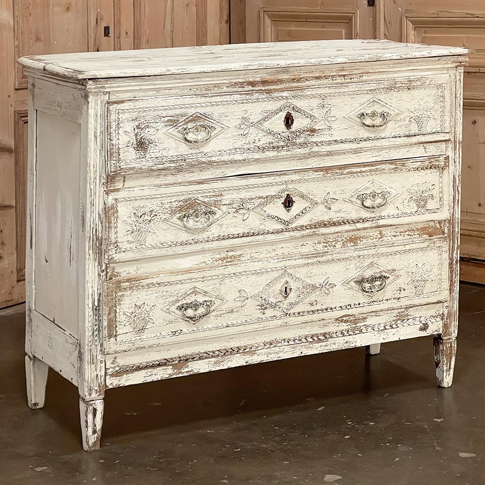Add timeless flair to your decorating with this superb 18th Century Country French Louis XVI Neoclassical Painted Commode! Featuring a wonderfully distressed painted finish with patina, it boasts and-carved detailing across the drawer facades and