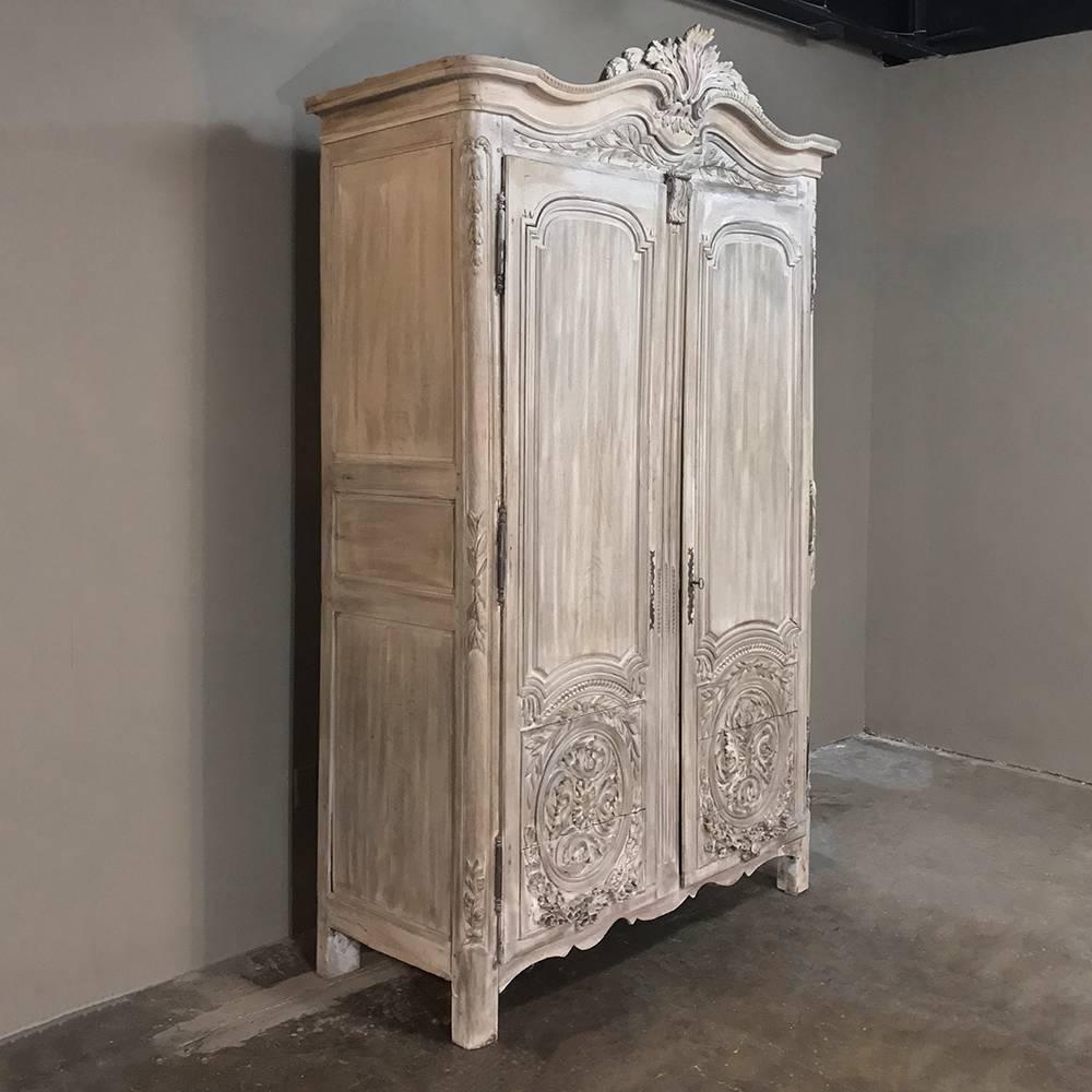 From the master artisans of Normandie comes this stunning and rare 18th century Country French Louis XVI period whitewashed armoire with sculpted floral and foliate motifs appearing in magnificent abundance from the arched crown to the door panels