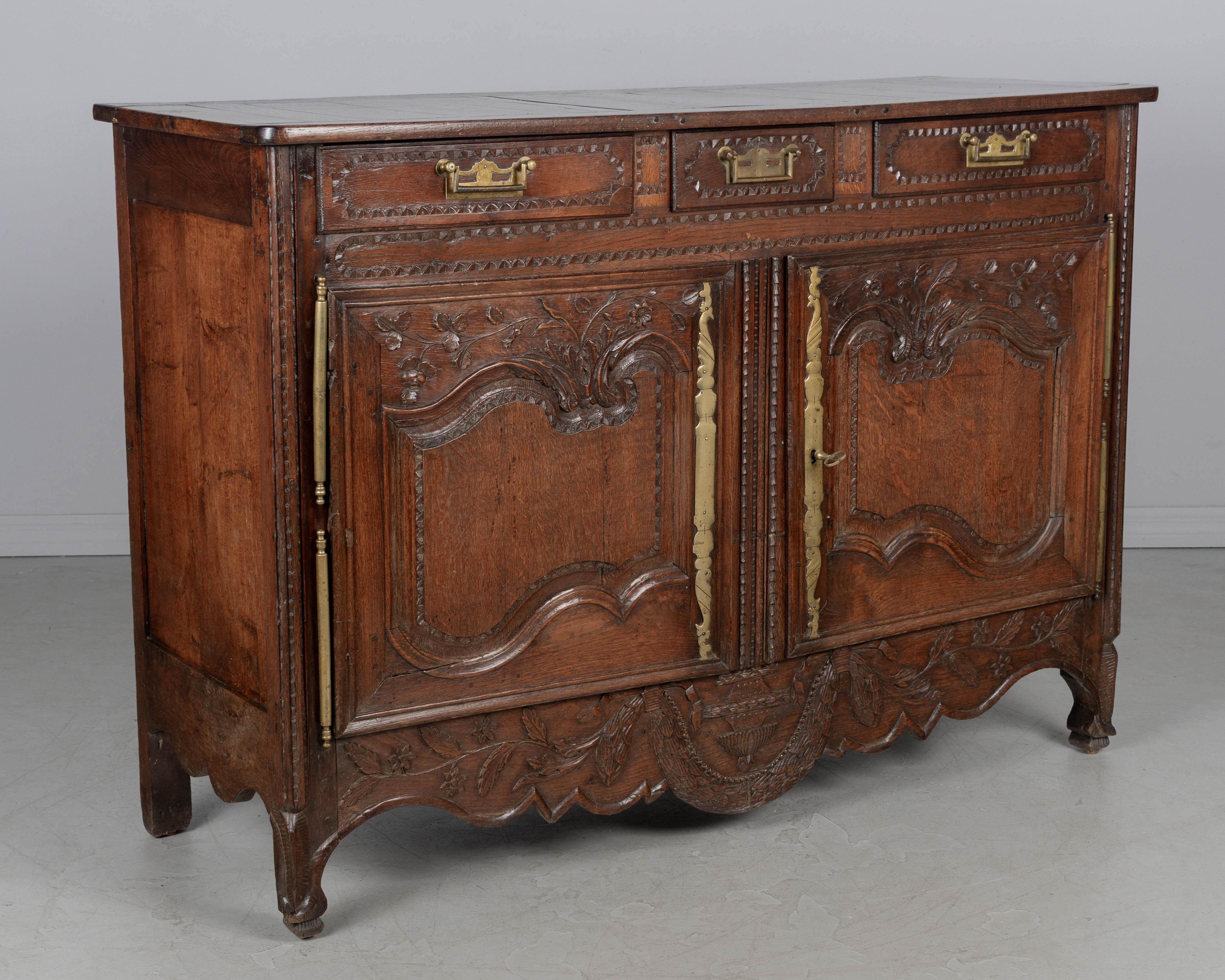 Un buffet francese di campagna del XVIII secolo in stile Luigi XV proveniente dalla Normandia, realizzato in rovere massiccio intagliato a mano con raffinati intagli a mano. Il buffet è dotato di tre cassetti a coda di rondine per riporre