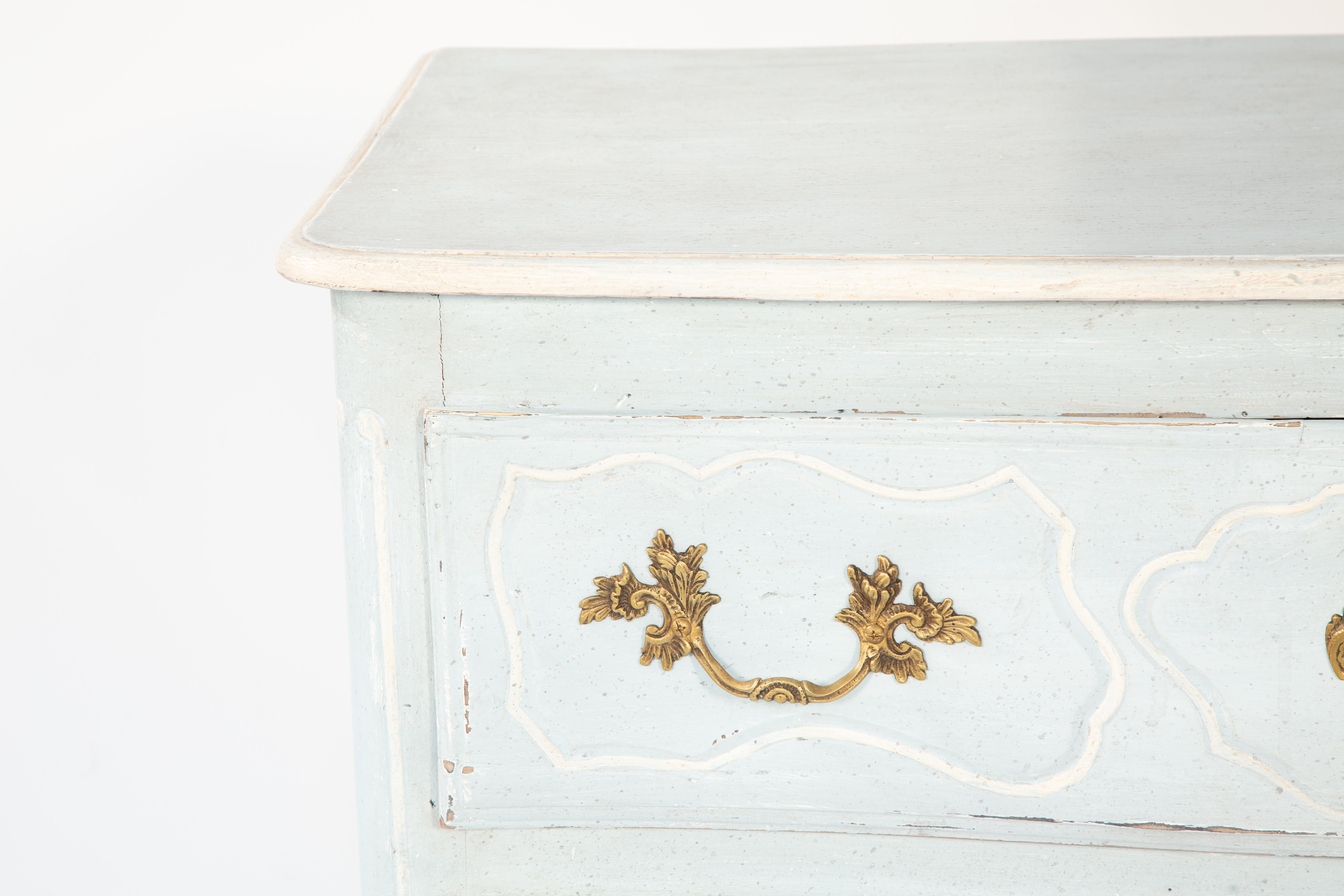 Antique French country commode, con finitura dipinta in blu pallido e avorio, il piano rettangolare modellato su cassetti a doppia pila con maniglie foliate in ottone e rosette abbinate, ciascuna delimitata da cornici intagliate, con pannelli