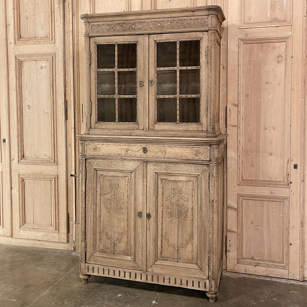 19th century Country French Louis XVI Stripped vitrine - cabinet is the ideal choice for a smaller space, providing display and storage yet requiring only about 4 feet of width on the wall! Timeless neoclassic motifs are hand carved into the facade