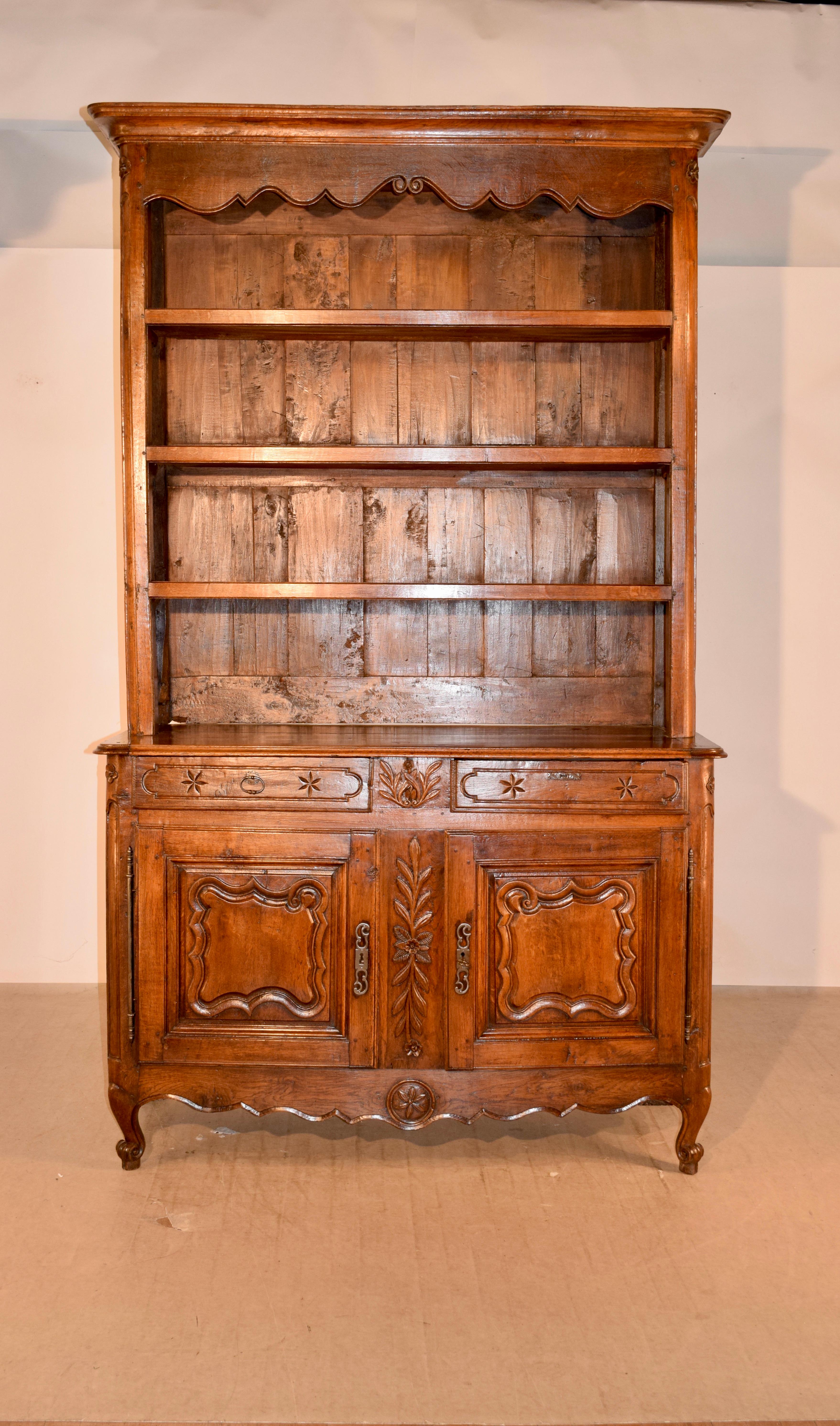 18th century country French wall cupboard made from oak. This is a magnificent piece. It has a detachable crown, following down to a hand scalloped frieze and three hand hewn shelves, all with plate rails. The sides of the piece are raised paneled,