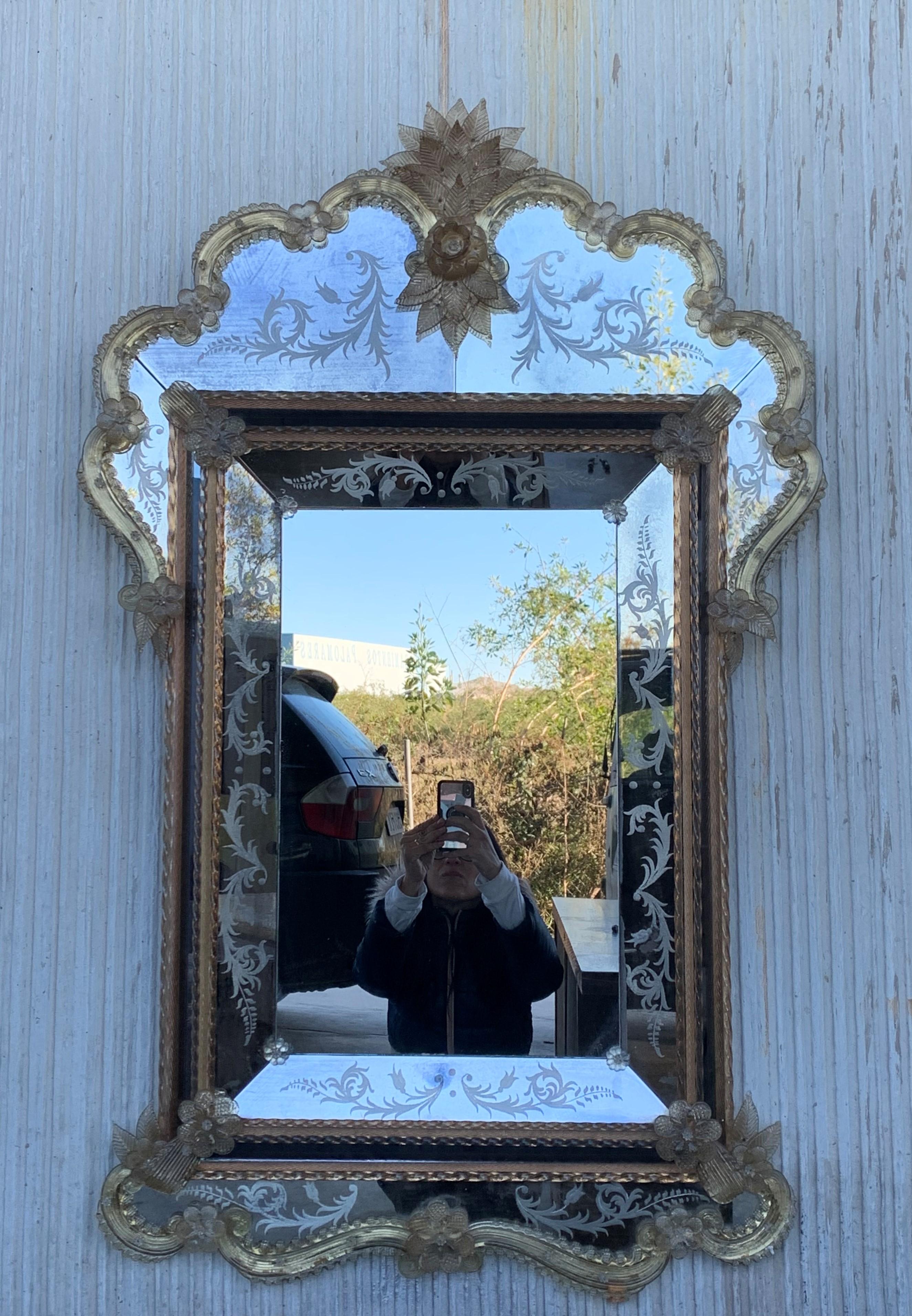 Der venezianische Spiegel mit Kammaufsatz. Der Spiegel mit abgeschrägten Paneelen und geschnitztem Wappen mit einem hübschen lotusblütenähnlichen Motiv ist handgefertigt und von Hand versilbert. Die mittlere Platte weist eine leichte Antikisierung