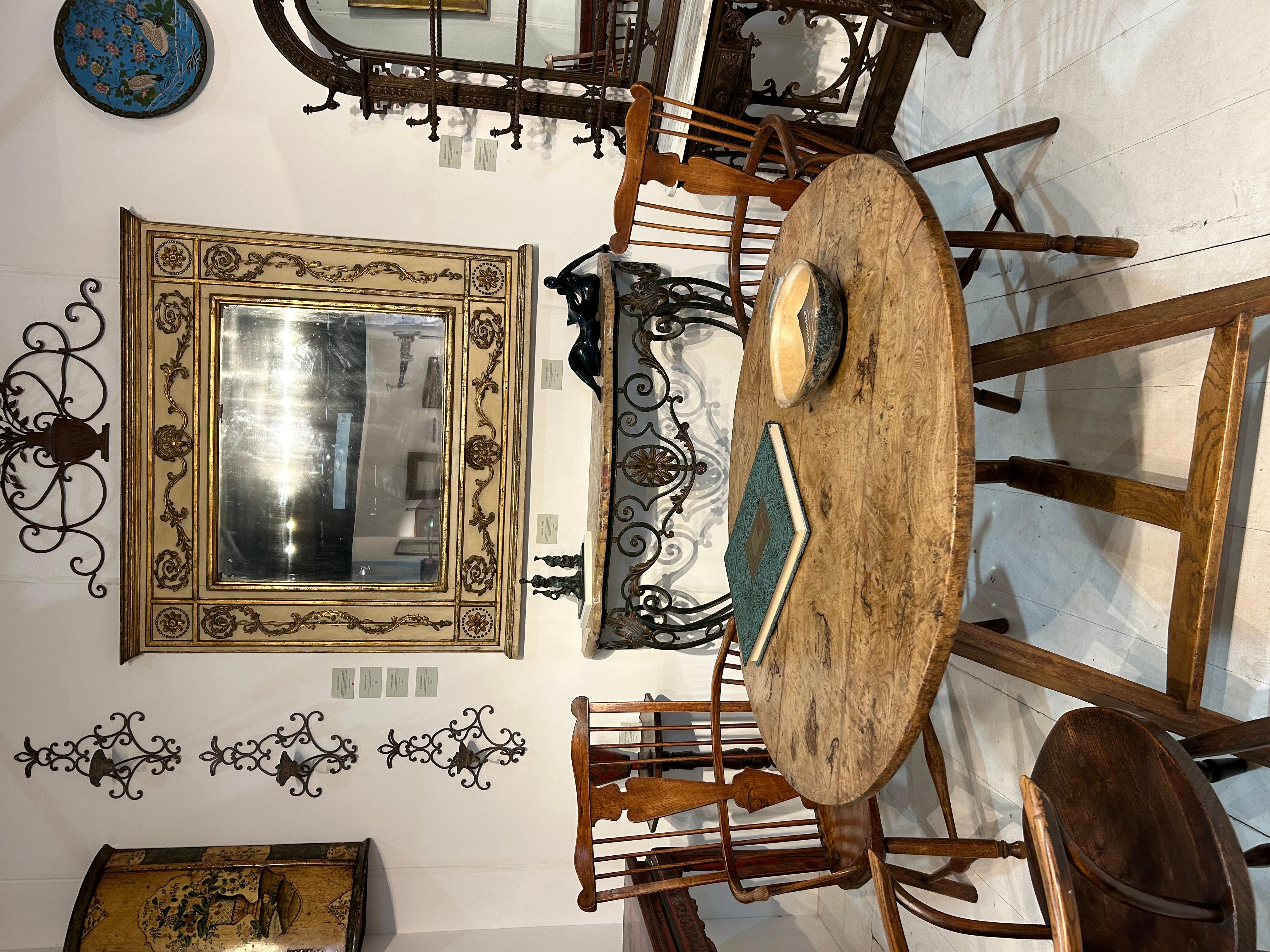 The antique round tilt-top burr ash cricket table is an iconic piece of furniture, noted for its unique three-legged design. It boasts a circular top held up by legs that elegantly splay outward. This table showcases the exceptional craftsmanship