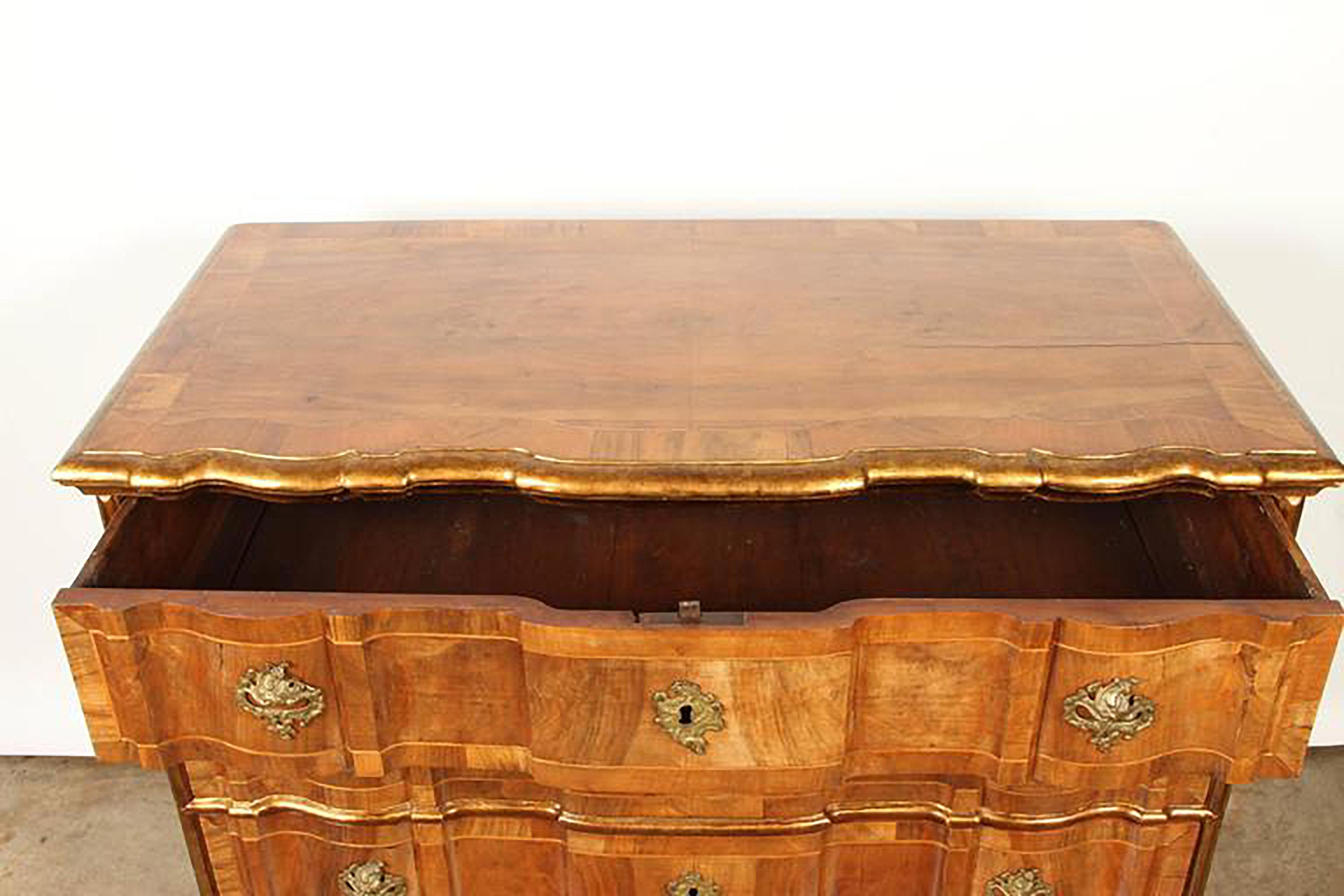 A Danish rococo chest of drawers, consisting of four drawers, with gilt bronze hardware and gilt borders. This Danish chest is veneered in walnut and has banding on each drawer.