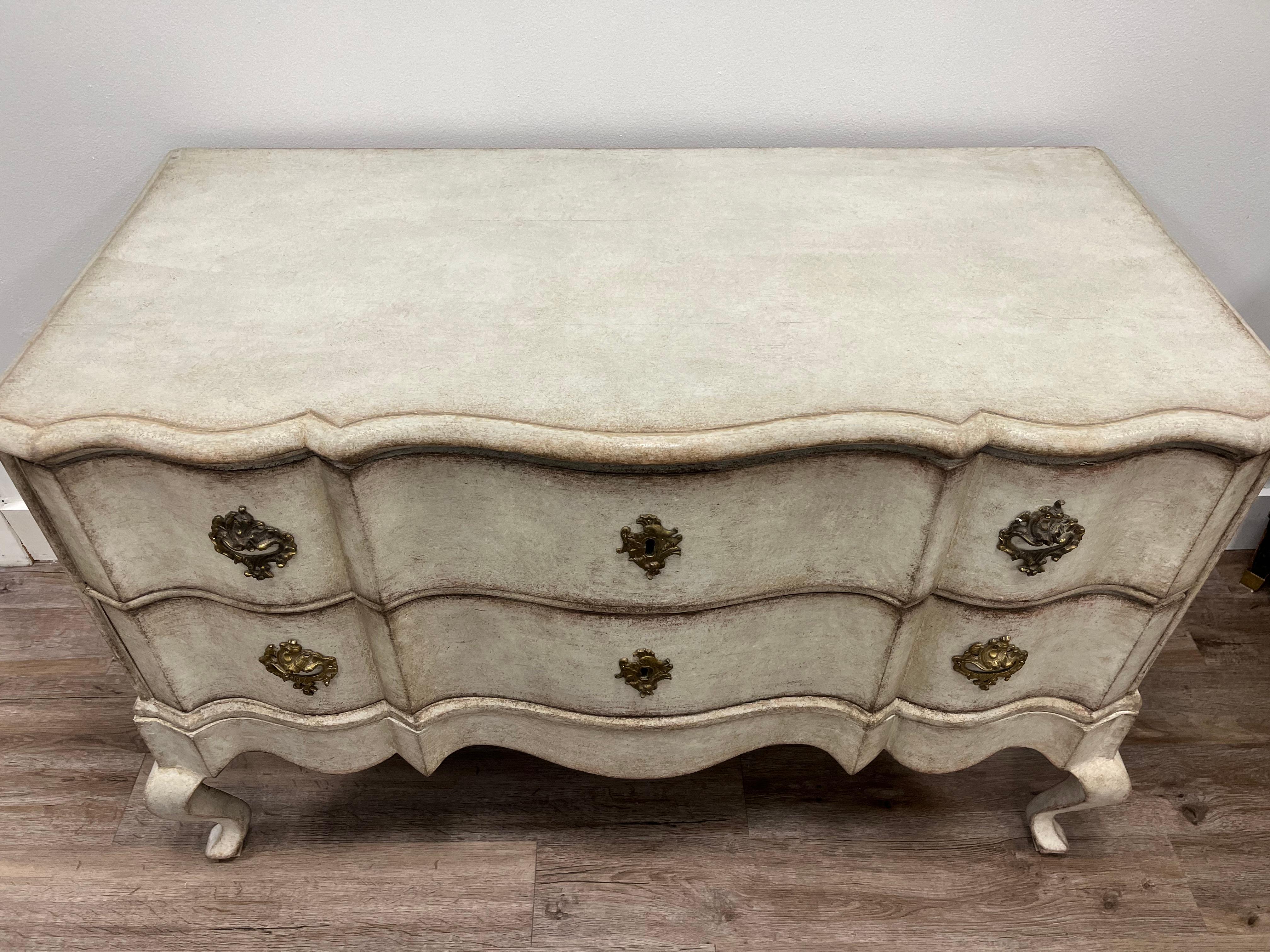 Cassettone a due cassetti in stile rococò scandinavo. Frontali dei cassetti a serpentina e gambe cabriolet. Ferramenta originale in ottone e serrature in ferro. Vecchia vernice color crema. 