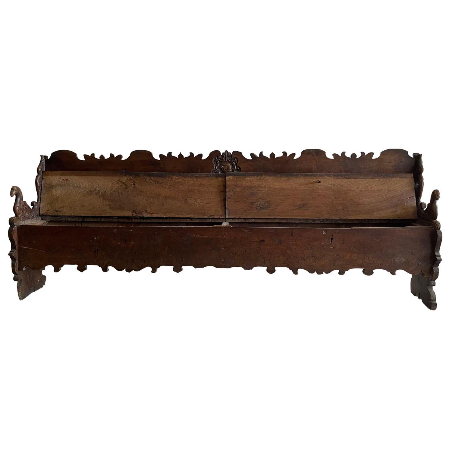 18th century late Renaissance, an antique, impressive Tuscan hand carved Walnut Cassapanca or storage bench with scrolled armrests depicting a pigeon design and Acanthus leaves, in good condition. The backrest is carved with very detailed ornaments