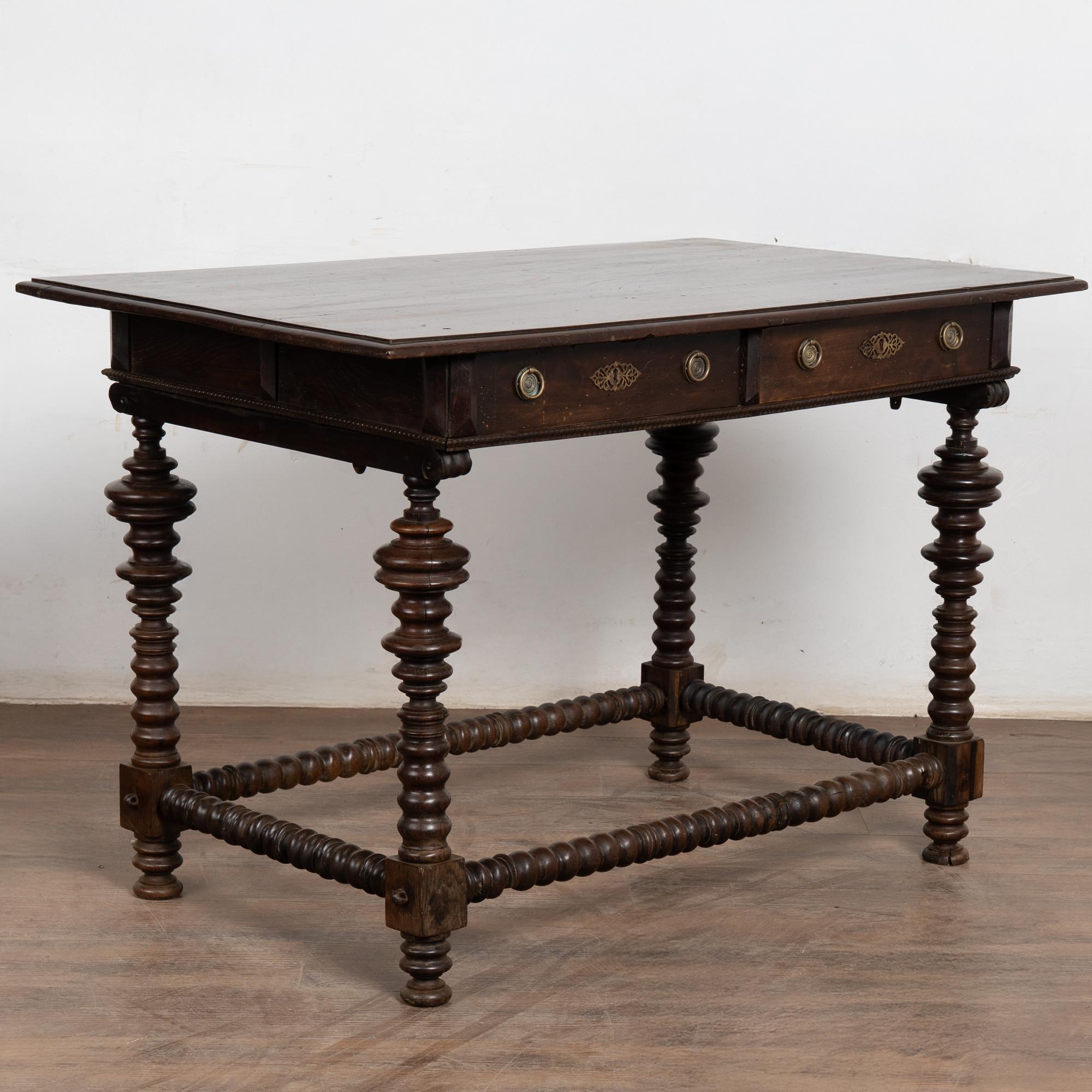 18th-century dark oak side table with elaborately turned legs, carved stretchers, and two functioning drawers. The reverse side features false-front drawers, allowing the table to stand freely. Two brass pulls on each drawer which functions